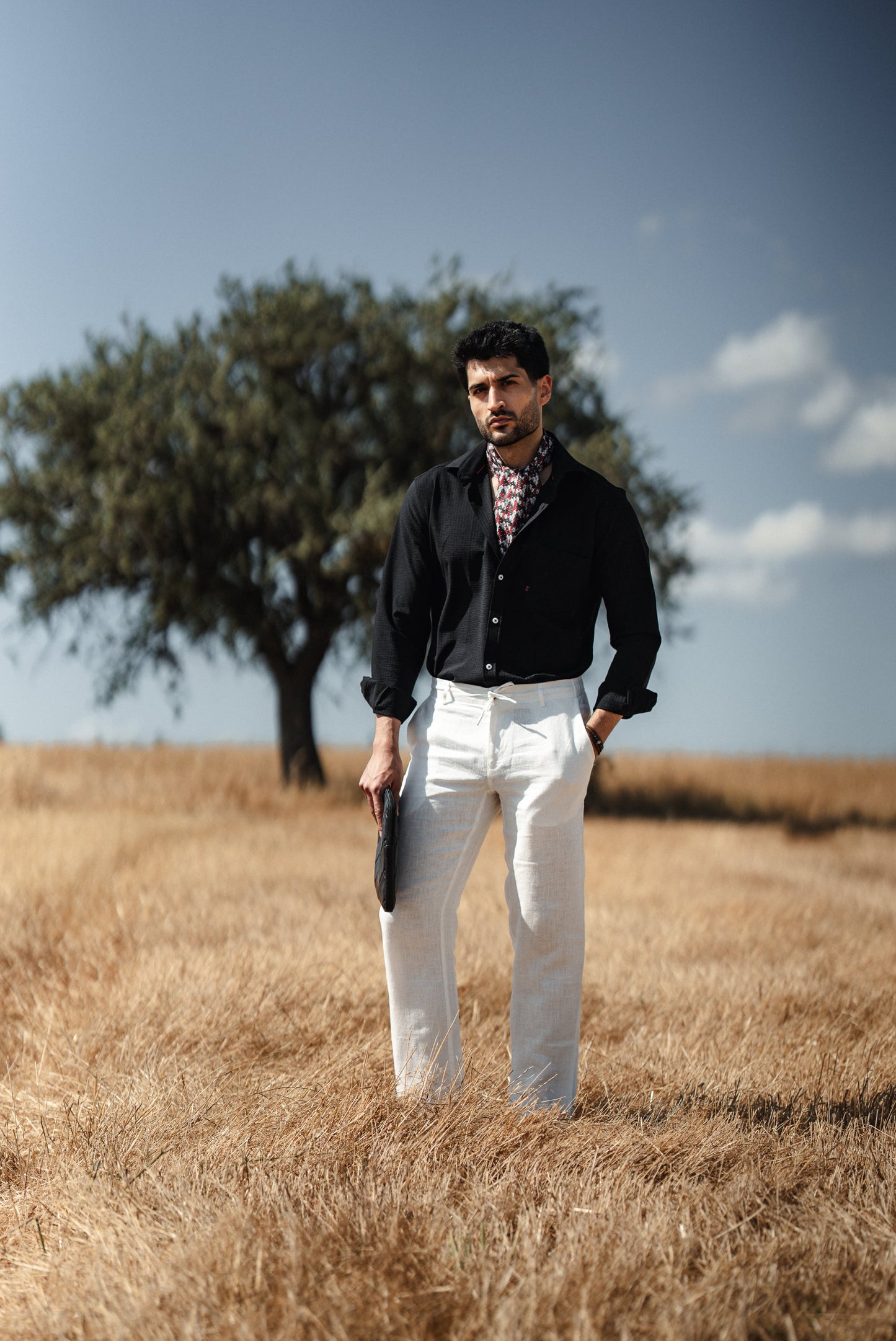 Man wearing a black linen button-down slim fit shirt, paired with chinos and loafers, exuding summer elegance on a Mediterranean terrace.