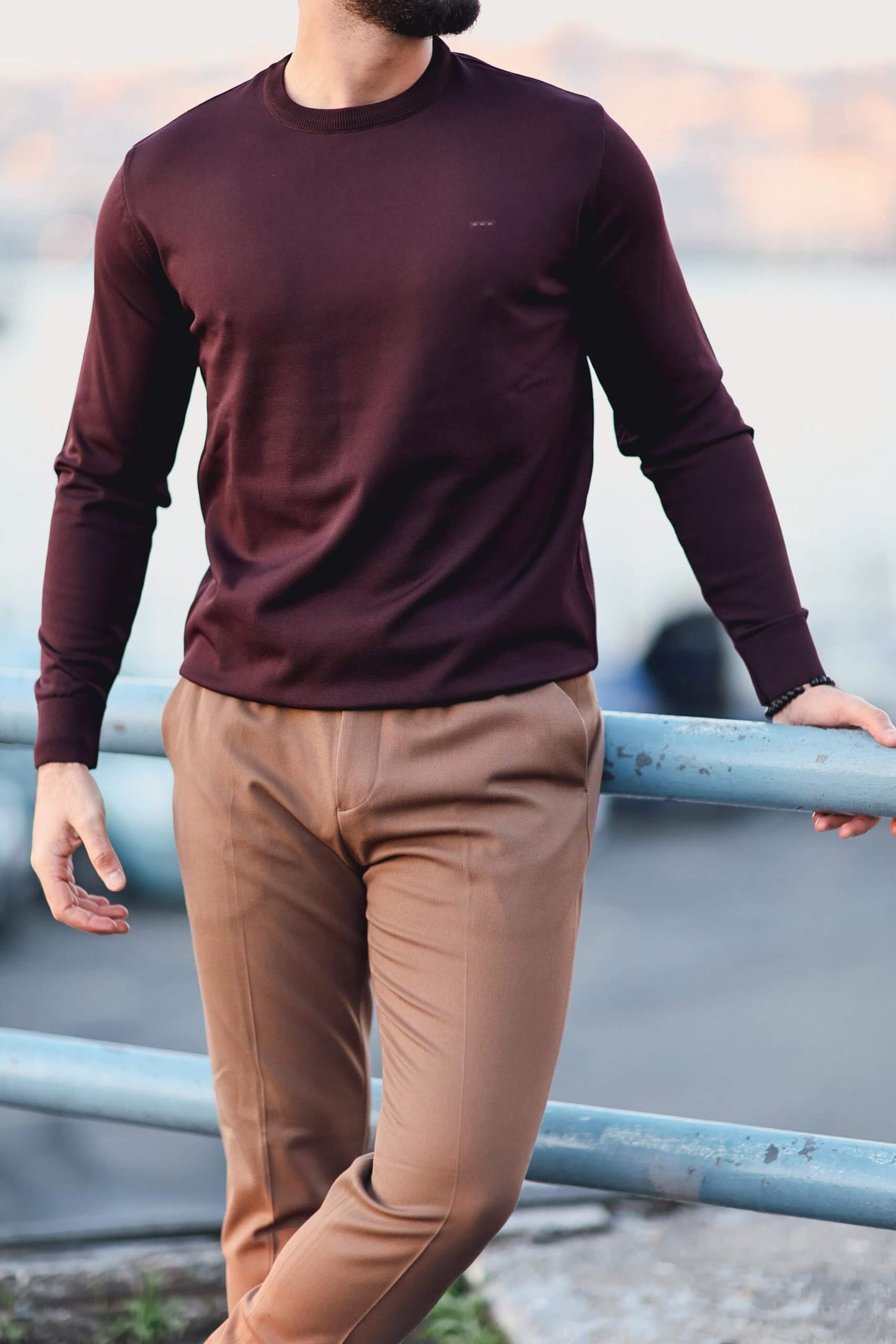 Men’s cherry long-sleeve knit sweatshirt styled with camel trousers outdoors