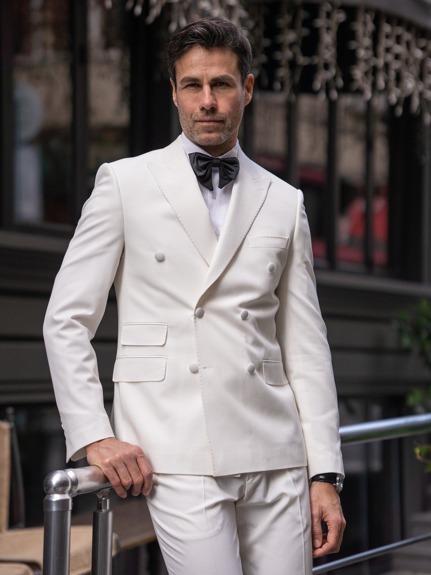 Men’s white slim-fit double-breasted suit with peak lapel blazer and tailored trousers, featuring a six-button design, double vents, and a modern structured silhouette for formal occasions.