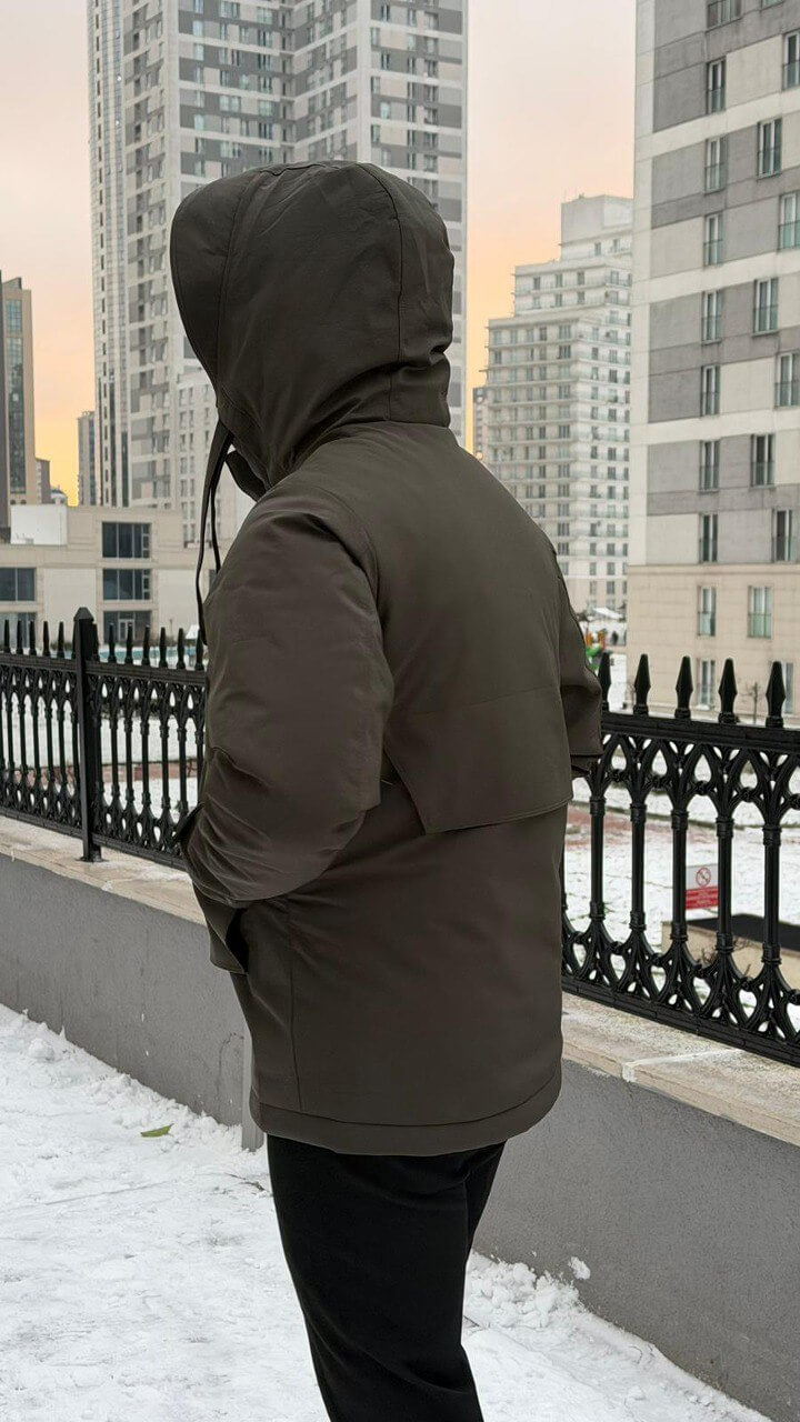 Men’s matte khaki technical winter parka with storm hood and reinforced chin guard, wind-resistant water-repellent polyester shell with stretch, oversized flap pockets and adjustable cuffs, urban commuter outerwear.