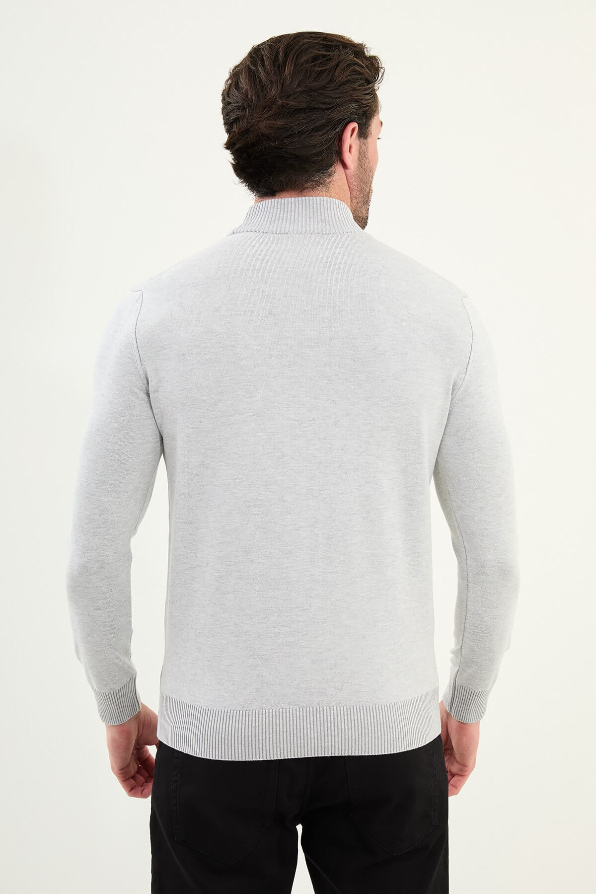 Man wearing a slim fit light grey mock turtleneck sweater with ribbed cuffs and hem.