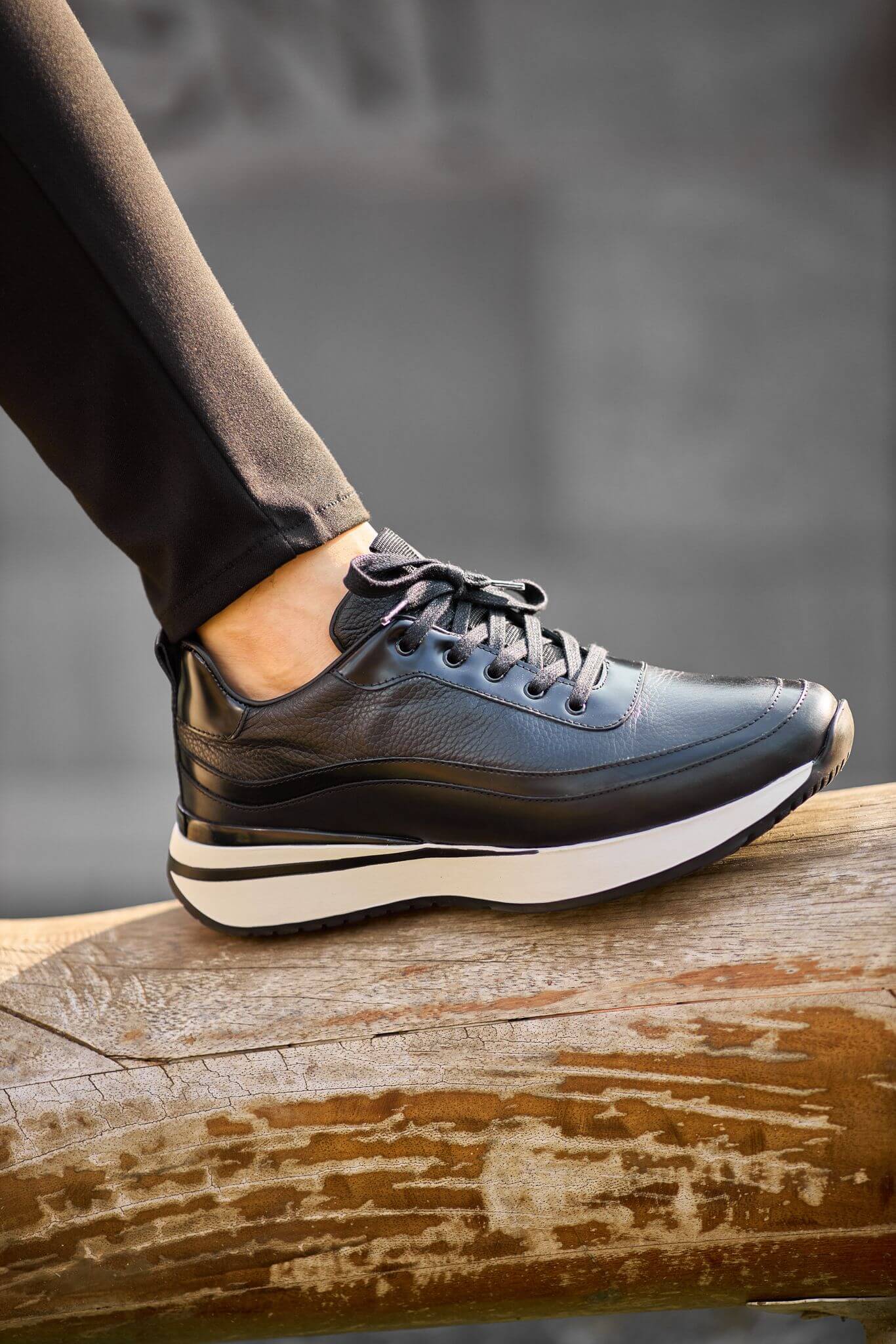 Men’s black leather elevated-sole sneakers on brick steps – premium casual footwear