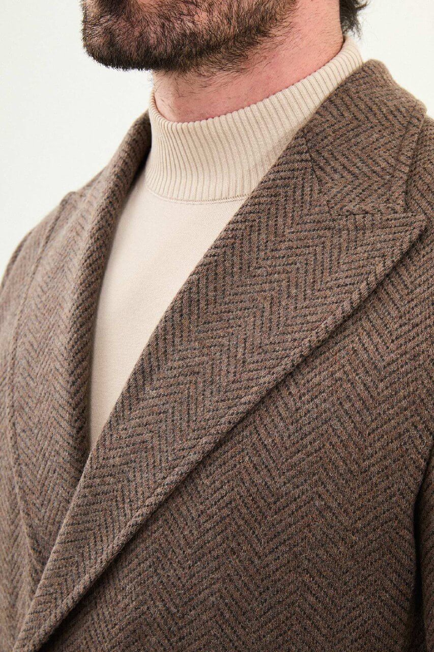 Full-body view of a man modeling a brown slim fit double-breasted coat with wide lapels, styled with dark trousers and brown Chelsea boots.