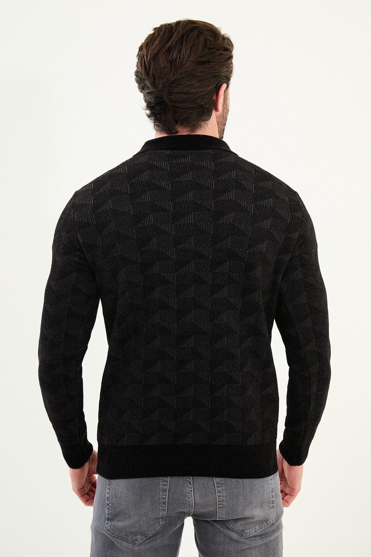 A man wearing a black patterned slim fit knitwear sweater with polo collar and half-zip closure.