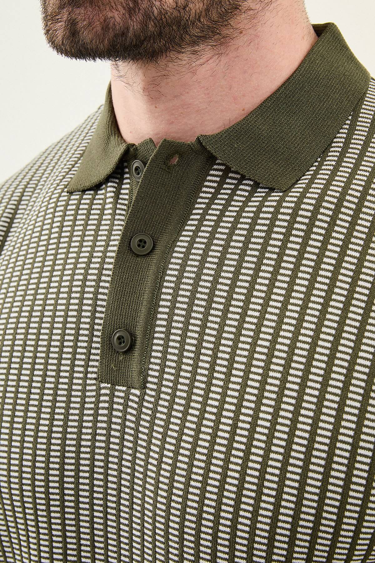 Men’s white striped slim fit knit polo shirt styled with dark trousers for an elegant summer smart-casual outfit.