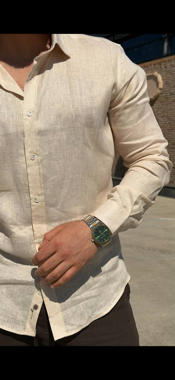 Man wearing a beige linen long-sleeve collared shirt, standing outdoors with a casual fit, styled with dark trousers.