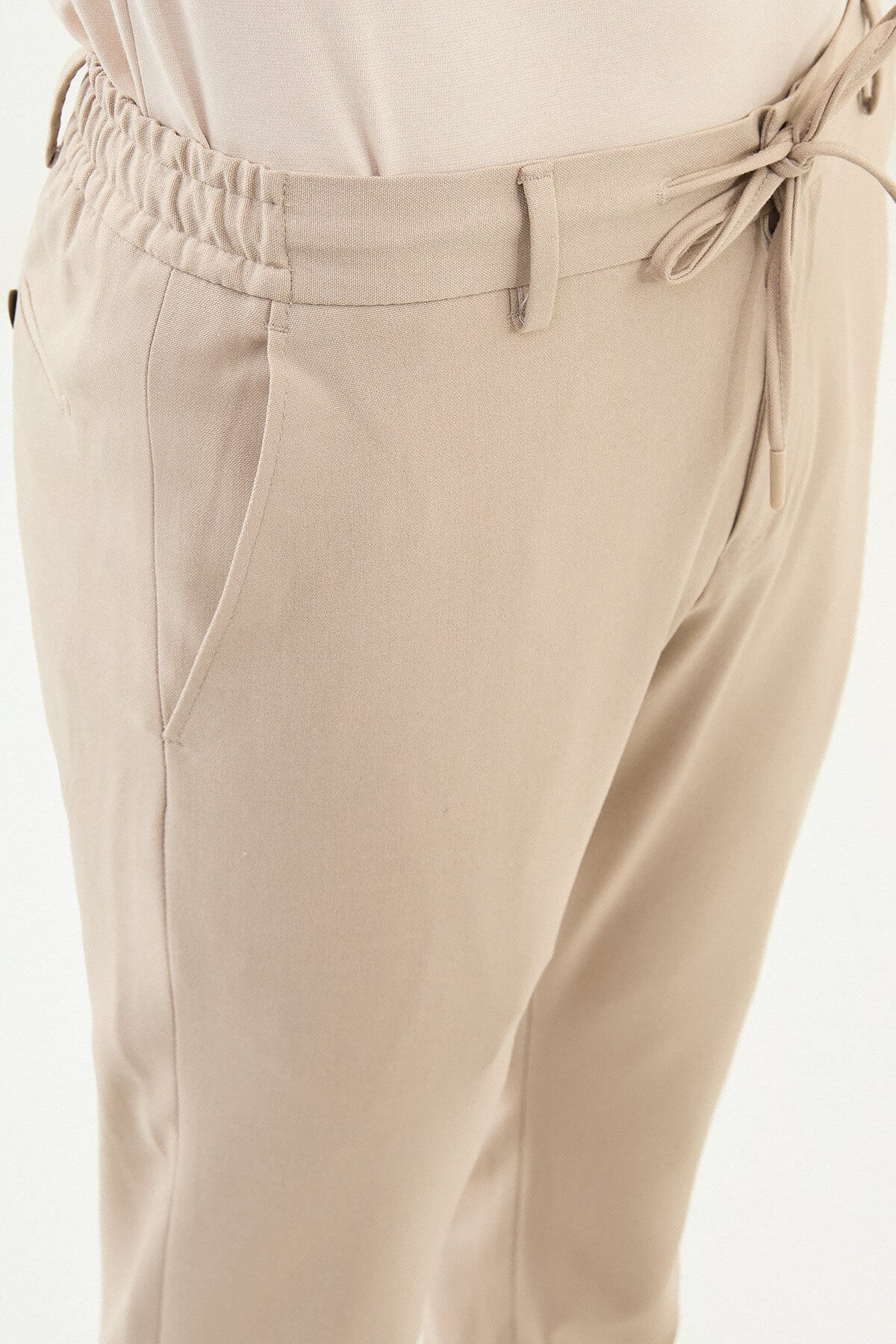 Man wearing beige slim-fit drawstring trousers with elastic waistband, styled with loafers and a summer shirt for versatile summer menswear.