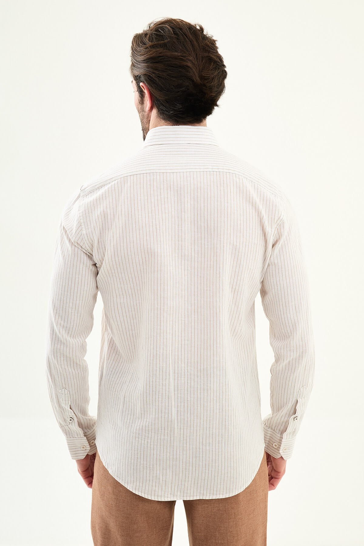 beige slim-fit long sleeve shirt with subtle stripe detailing, pocket accent, and tailored cuffs, paired with light trousers