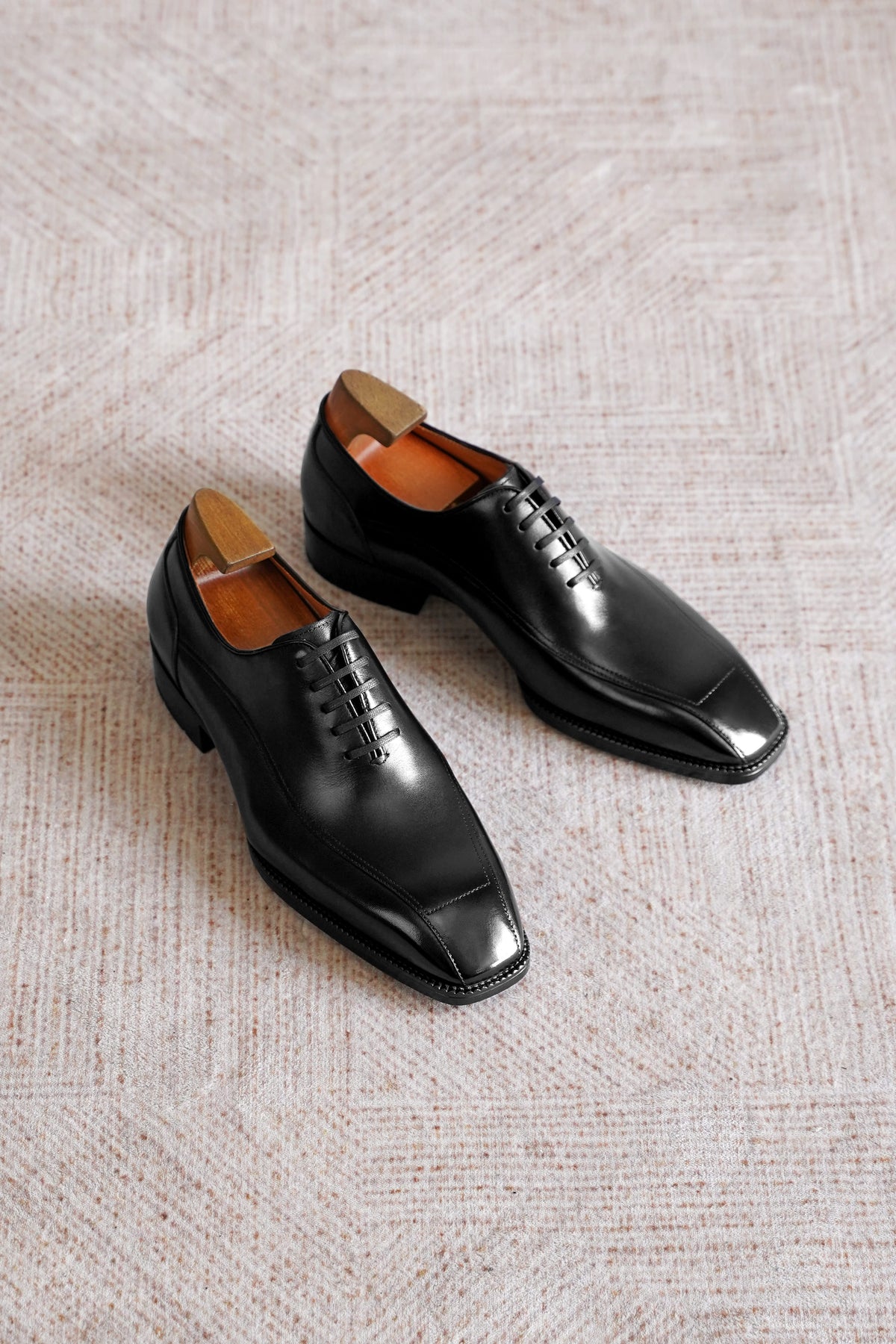 Men’s black leather wholecut Oxford dress shoes with sleek lace-up design, polished finish, and elegant formal silhouette.