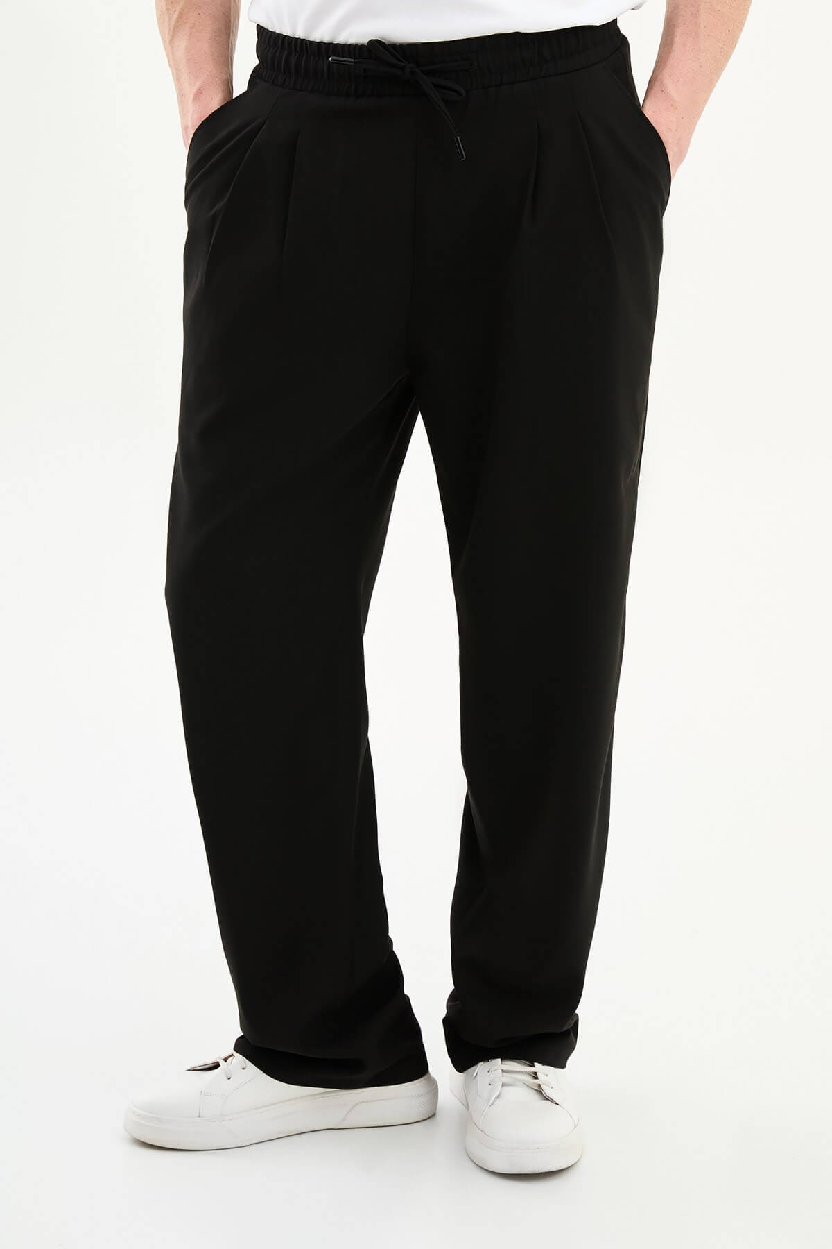Men wearing black luxe drawstring jersey pants with white sneakers, styled for smart-casual summer occasions.