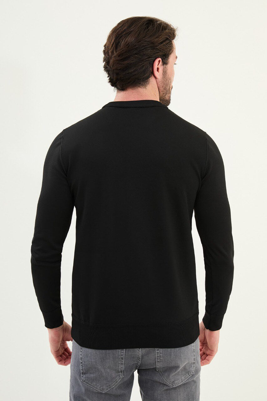 Men’s slim-fit black crew-neck sweater with geometric ‘T’ textured knit front panel, cotton-viscose-elastane blend, styled with charcoal gray denim in a monochrome winter outfit.