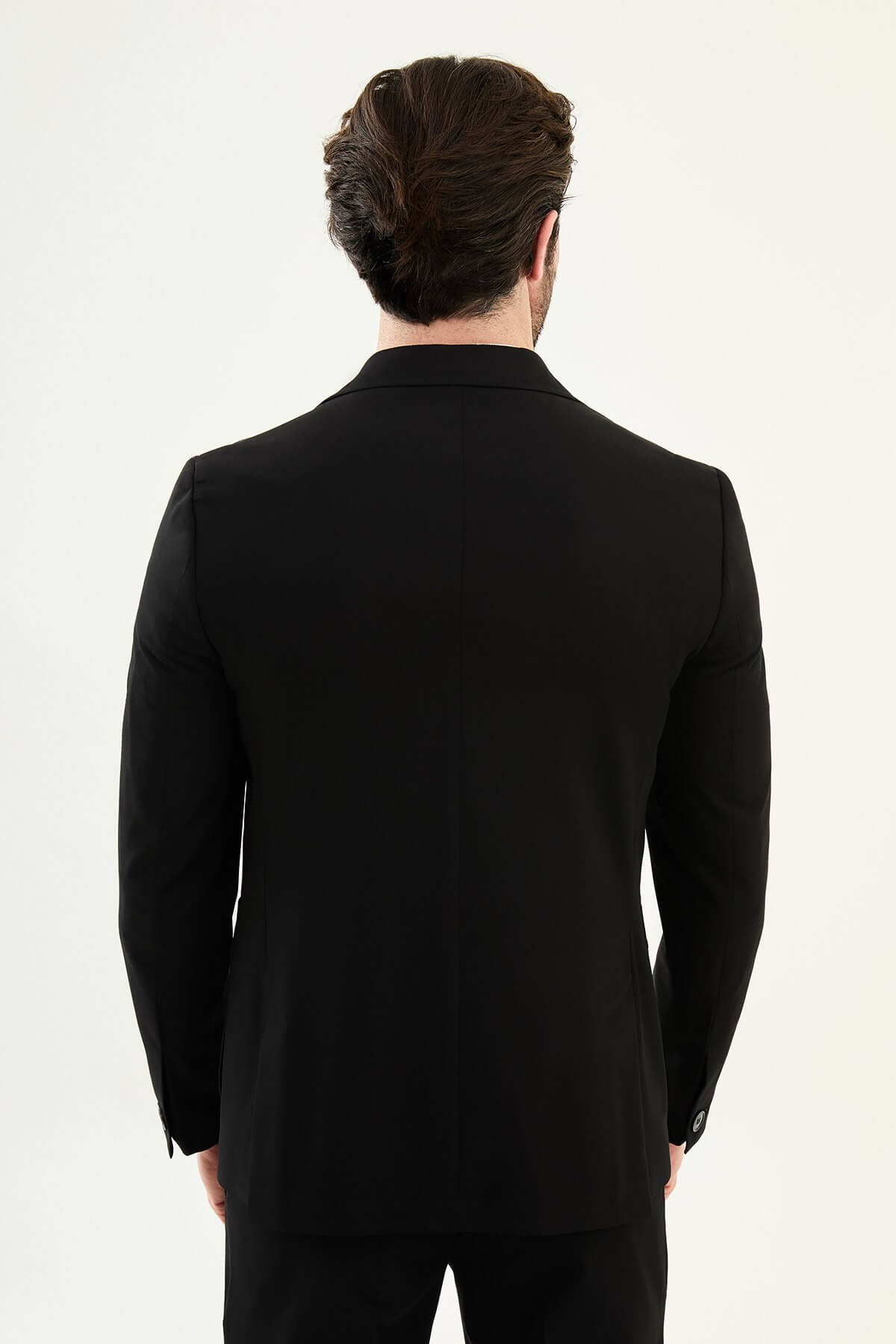 Close-up of a men's black slim fit single-breasted blazer with notched lapels and front pockets, styled over a white shirt for a modern formal look.