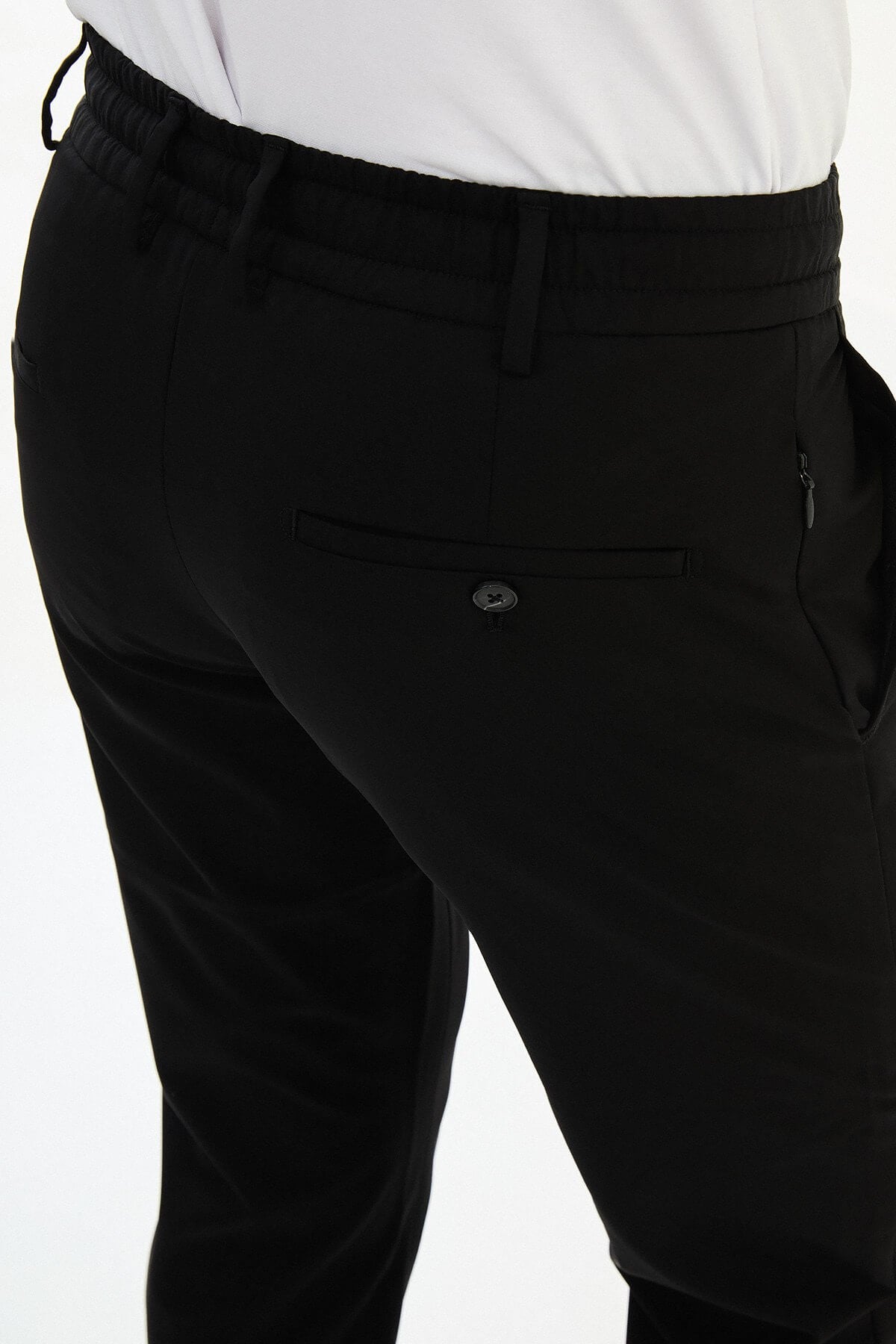 Man wearing black slim-fit summer trousers styled with white sneakers and a light summer top.