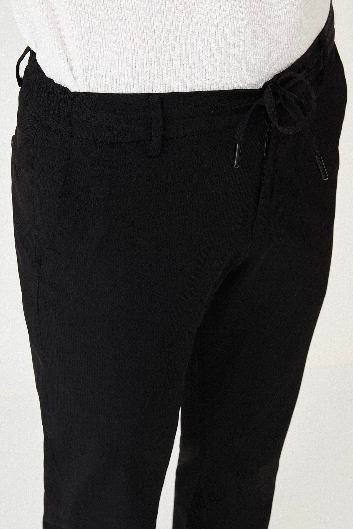 Man wearing black slim-fit summer trousers styled with a white polo shirt and black loafers.