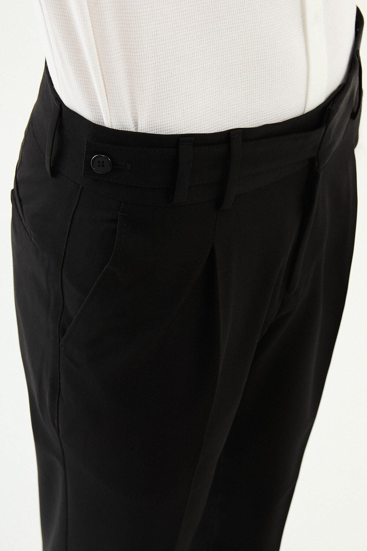 Man wearing black slim-fit straight-leg pleated trousers styled with a white dress shirt and black leather shoes, ideal for summer formal and business occasions.