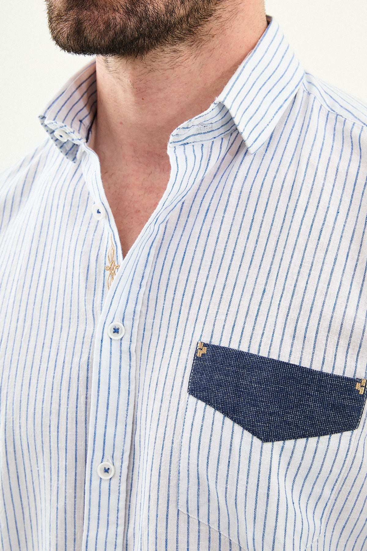 blue slim-fit long sleeve shirt with a contrasting pocket detail, standing indoors against a neutral backdrop