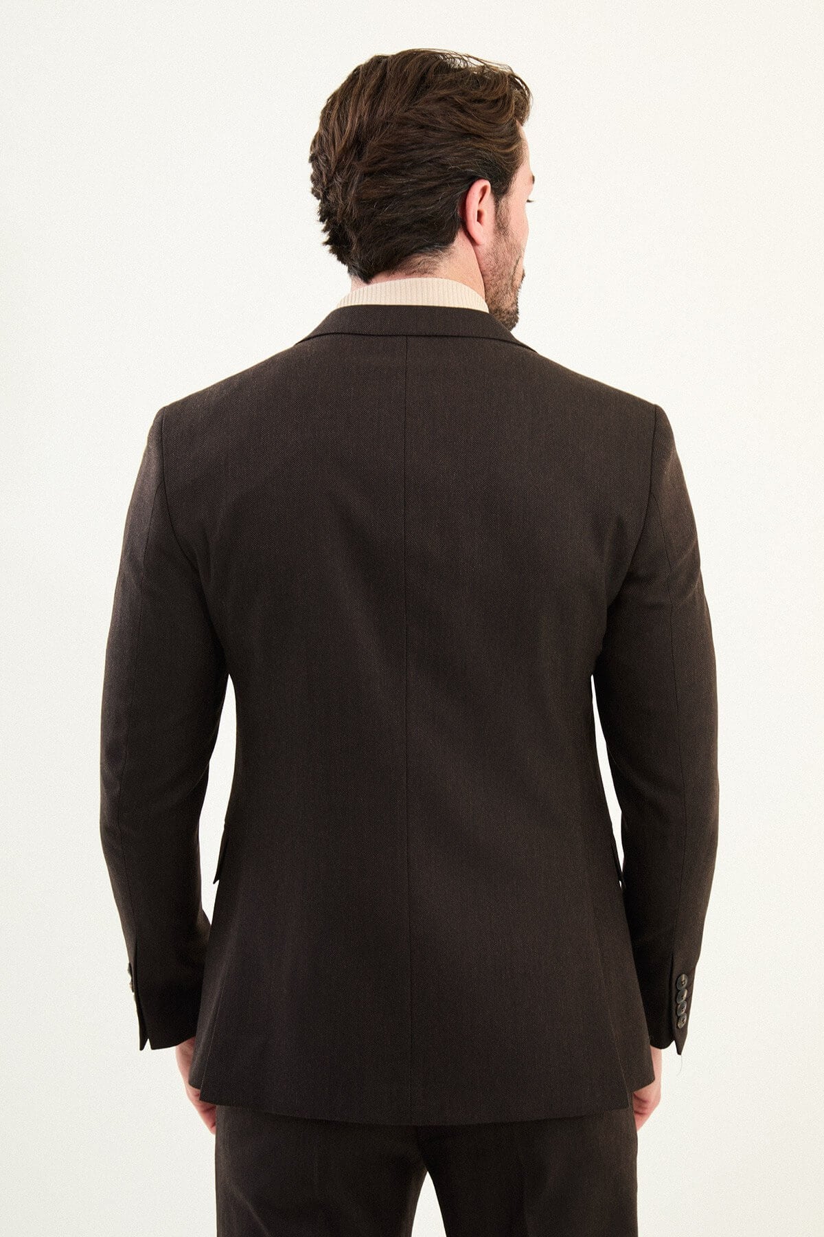 Men’s deep brown slim-fit single-breasted wool-blend suit with notch lapels and matte finish, high-wool fabric with stretch for winter wear, styled with a cream turtleneck for tonal dressing.