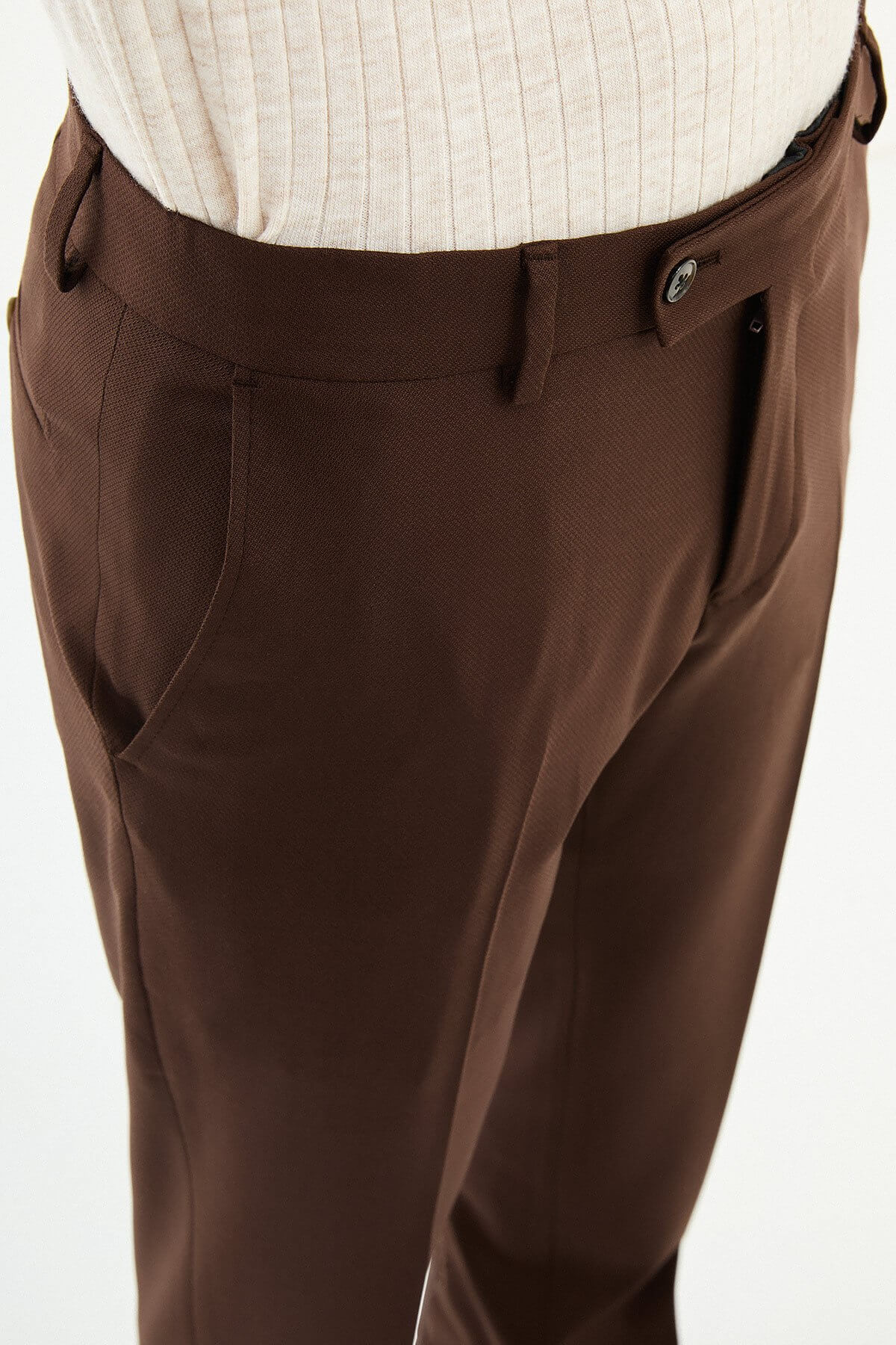 Man wearing brown pleated dress trousers with a straight slim fit, styled with a white shirt and brown leather shoes.
