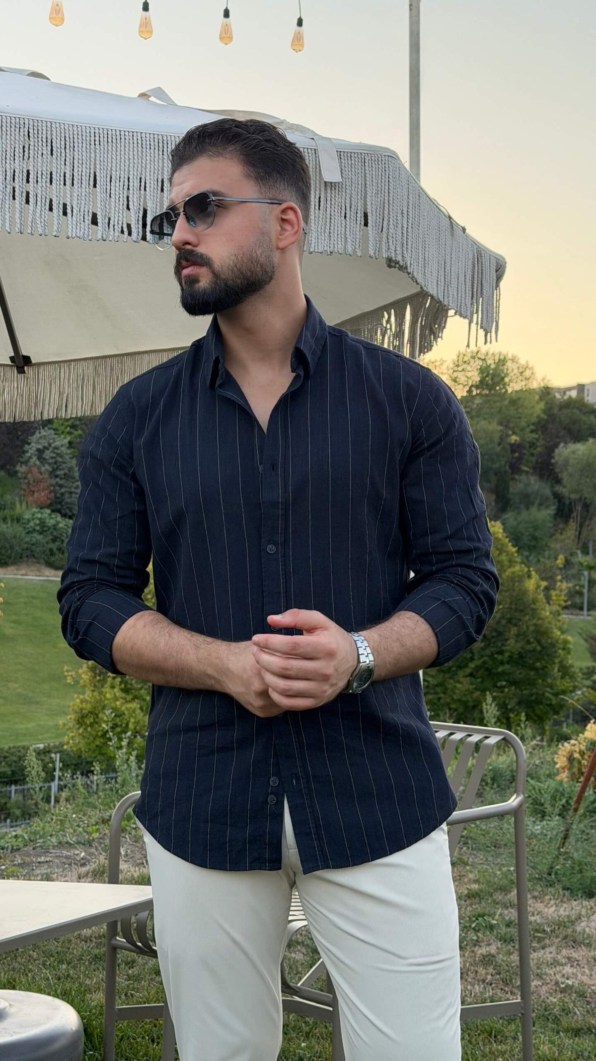 Men’s dark blue pinstripe long sleeve cotton shirt styled with white trousers and black loafers