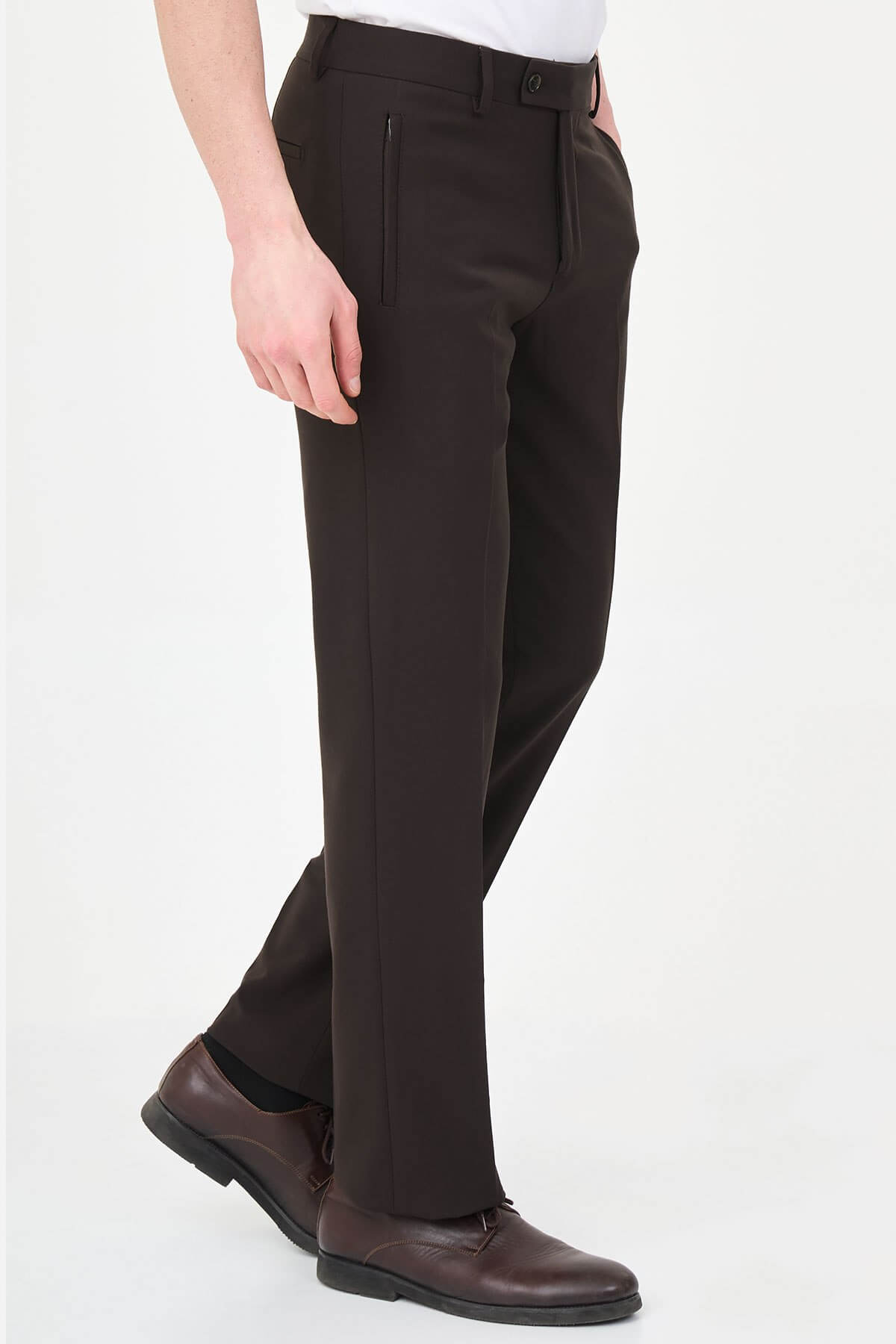Man wearing dark brown slim-fit dress trousers styled with a white shirt and brown leather shoes.