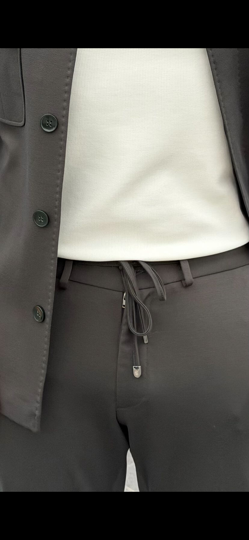 Men’s khaki elastic waist drawstring pants with tapered fit styled with white sneakers and smart casual jacket