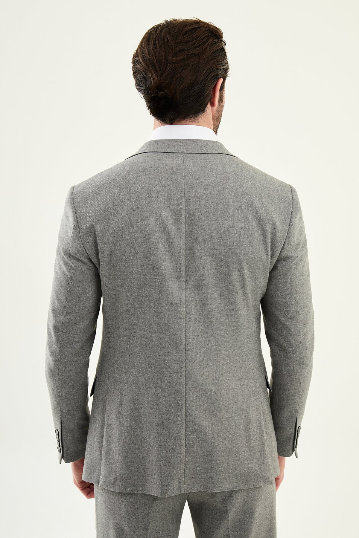 Man wearing a gray three-piece slim fit suit, including jacket, vest, and trousers, paired with a white dress shirt and black patterned tie