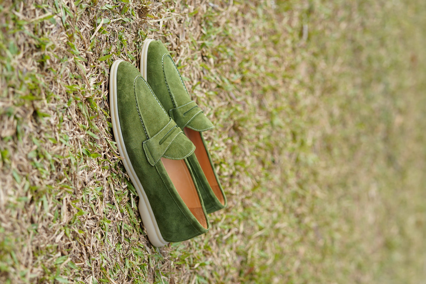 Men’s khaki green suede leather penny loafers with classic vamp strap detail and lightweight sole.
