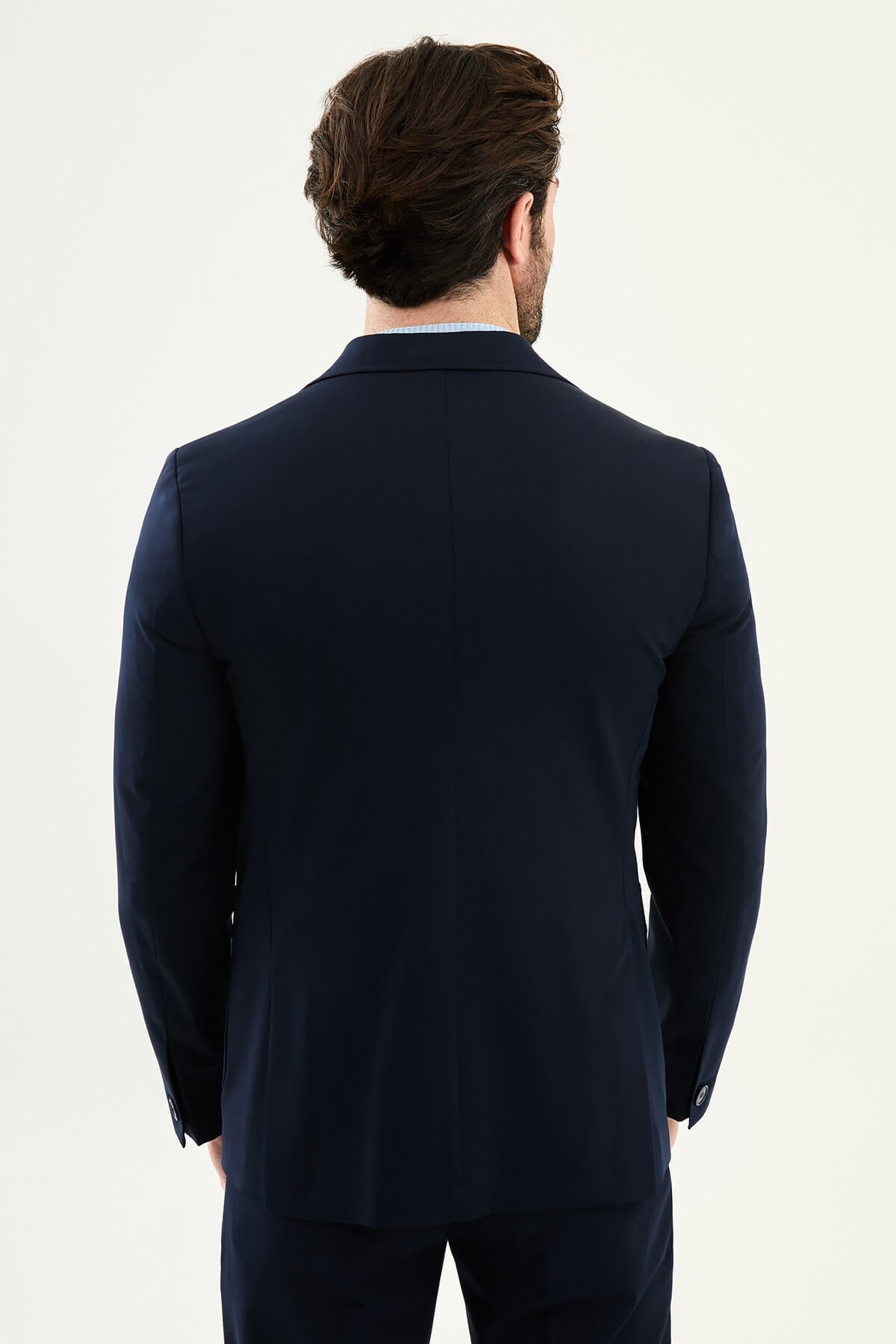 Men’s navy blue slim fit blazer with a clean modern design and stretch fabric, styled with a light blue knit top for elegant smart casual and formal occasions.