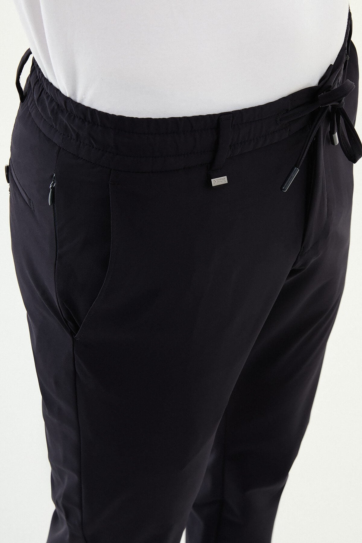 Man wearing navy blue slim-fit summer trousers styled with white sneakers and a short-sleeve summer shirt.