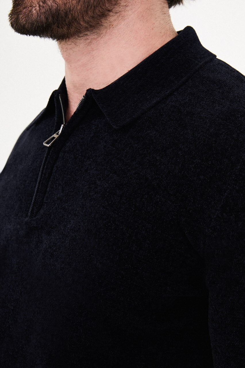 Men’s navy blue polo neck knit sweater with zip collar detail styled with dark trousers for a refined fall winter smart-casual outfit.