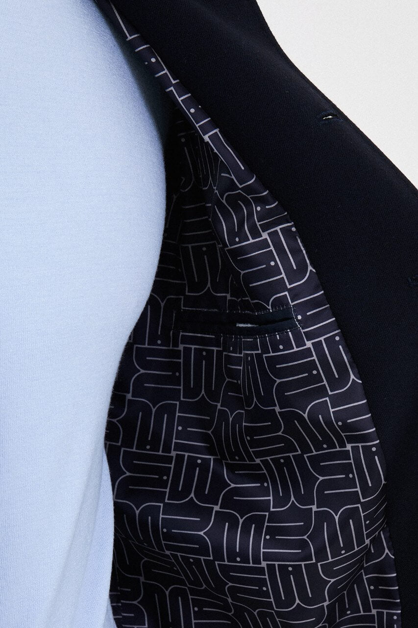 Men's navy blue fall jacket styled with a light blue sweater and dark trousers for a smart-casual look.
