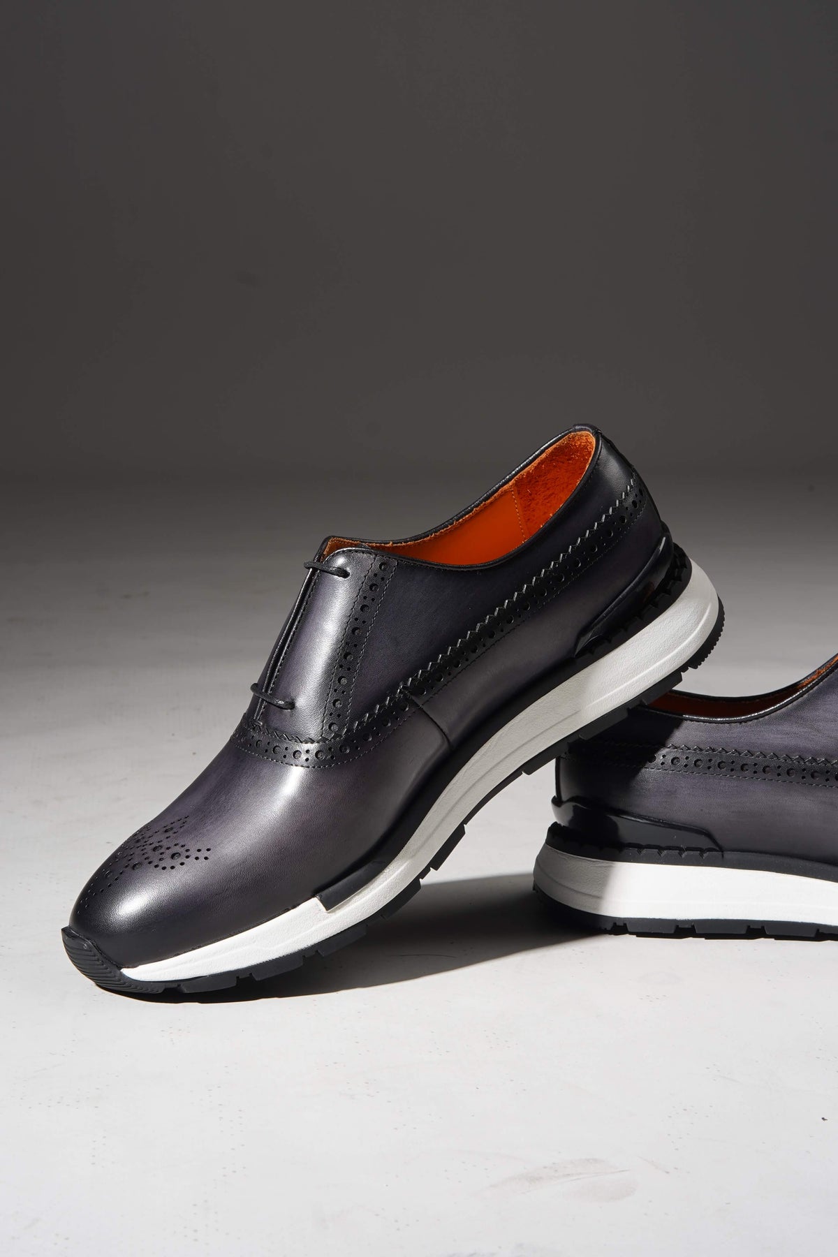 Navy brogue sneaker with minimal lace-up closure, profile view