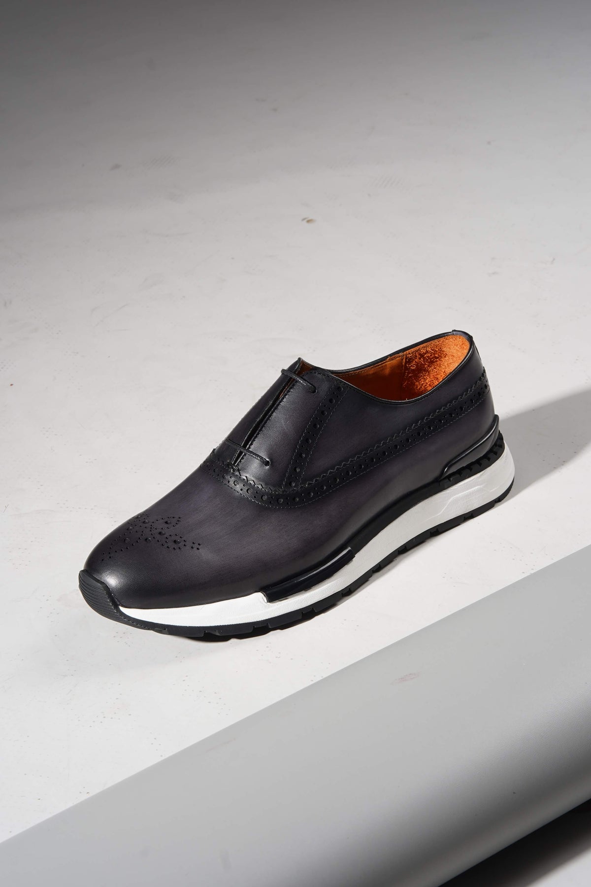 Navy leather minimal sneaker with brogue detailing, side view