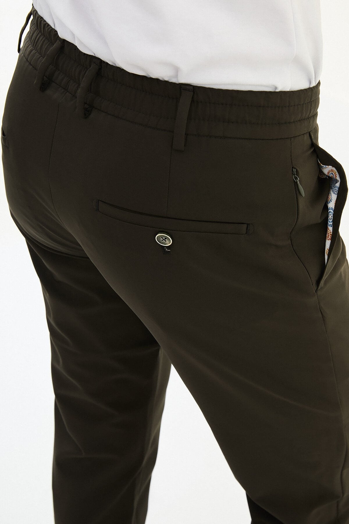 Man wearing olive green slim-fit summer trousers styled with a white polo shirt and casual sneakers.