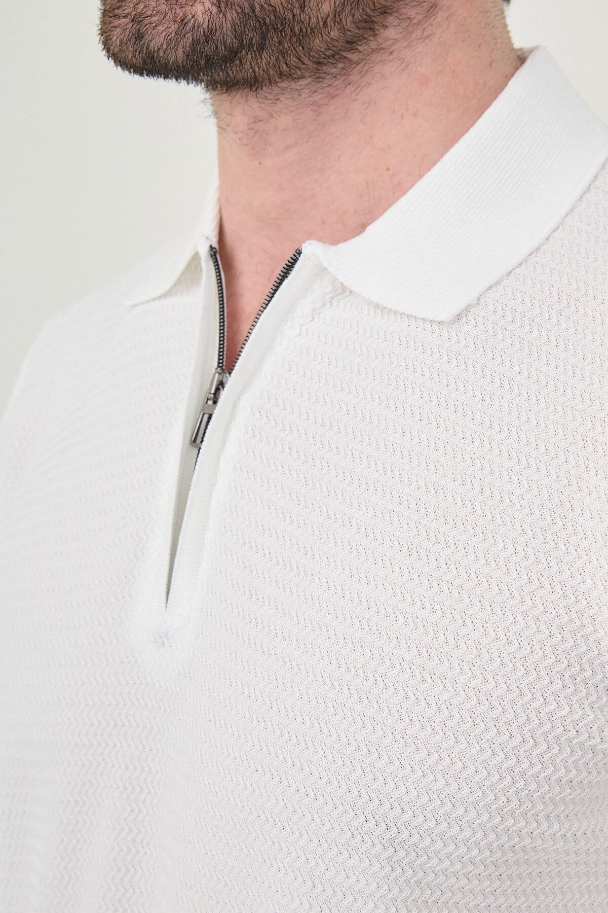 Man wearing white slim-fit quarter-zip polo t-shirt with dark stripe accents, styled with light brown trousers.