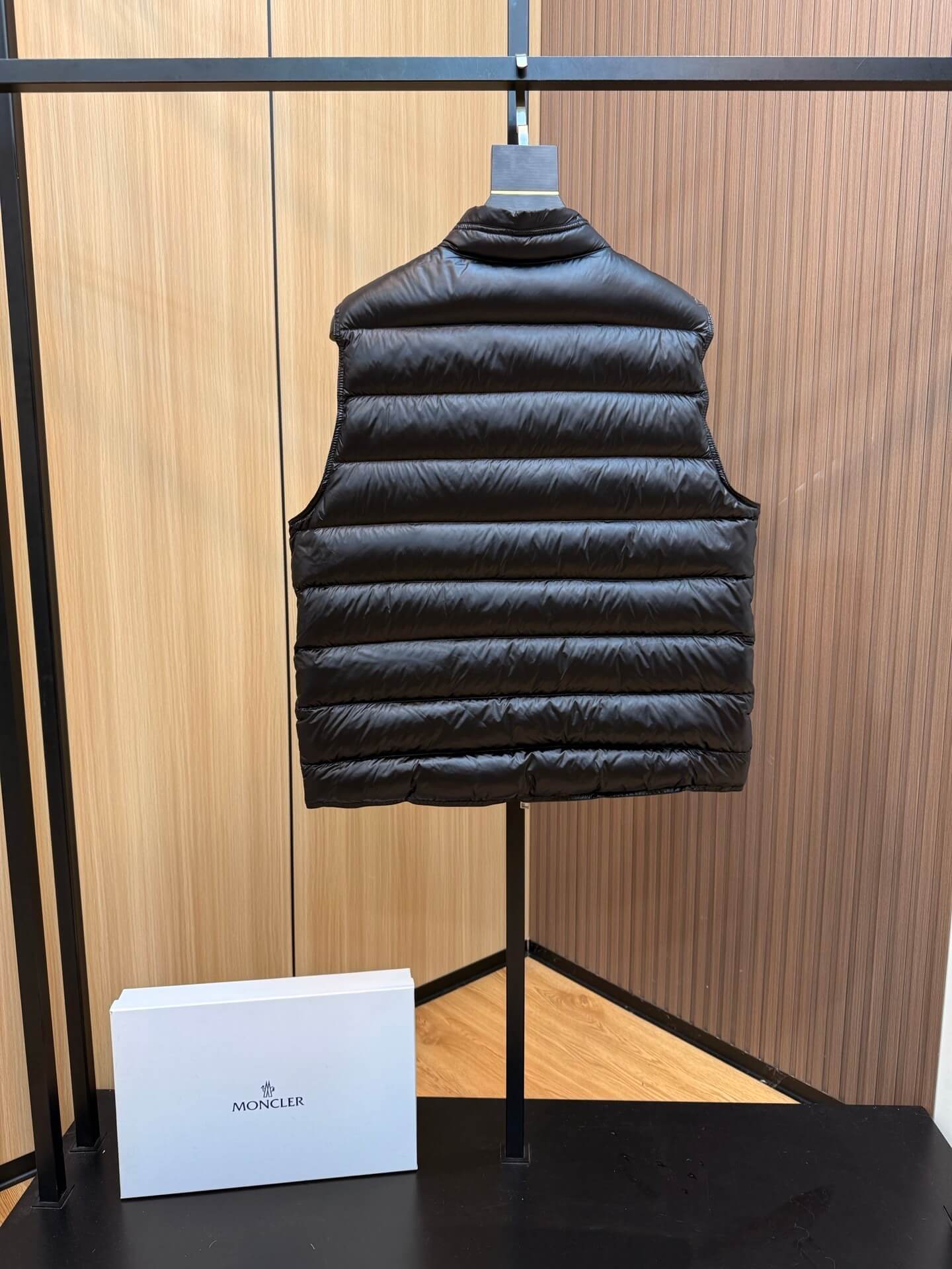 Black quilted down gilet with zip closure and chest logo patch, Moncler Gui-inspired design.