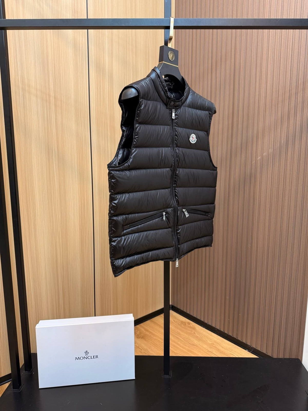 Black quilted down gilet with zip closure and chest logo patch, Moncler Gui-inspired design.