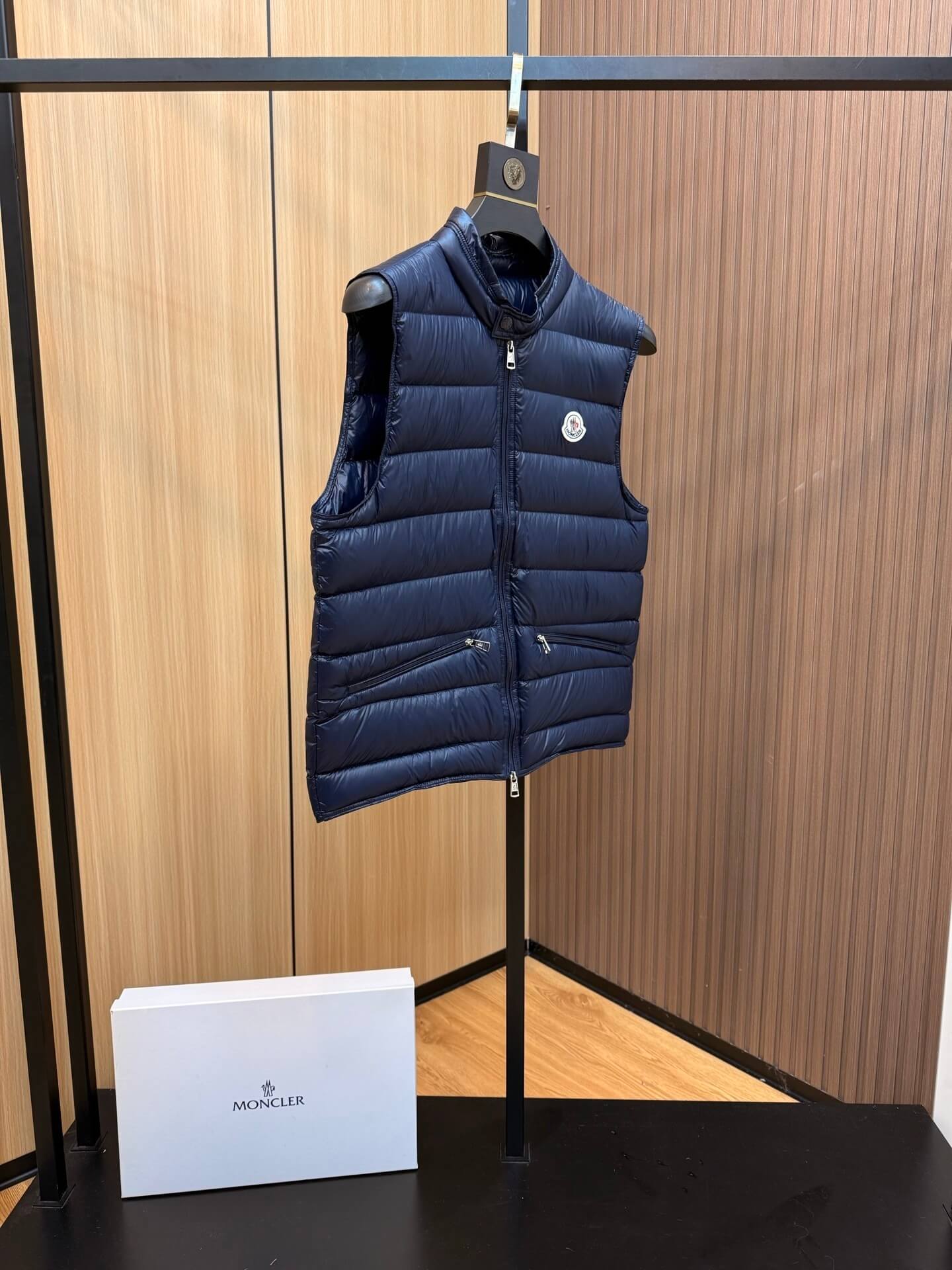 Navy blue glossy down vest with chest logo patch and zippered pockets, Moncler Gui-inspired.