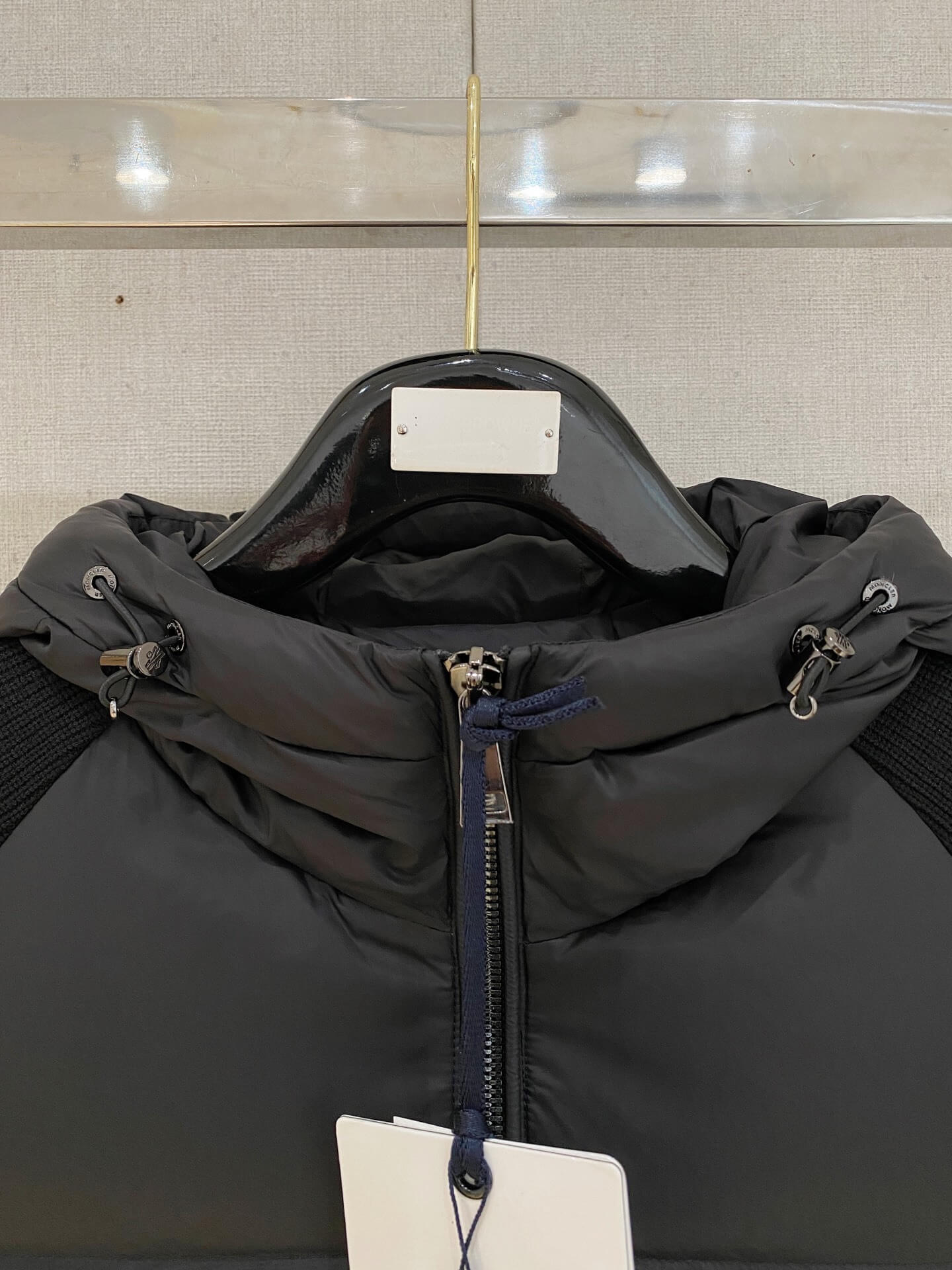 Black knit-sleeve down jacket with quilted front panels and hood, Moncler x Christopher Raxxy inspired design.