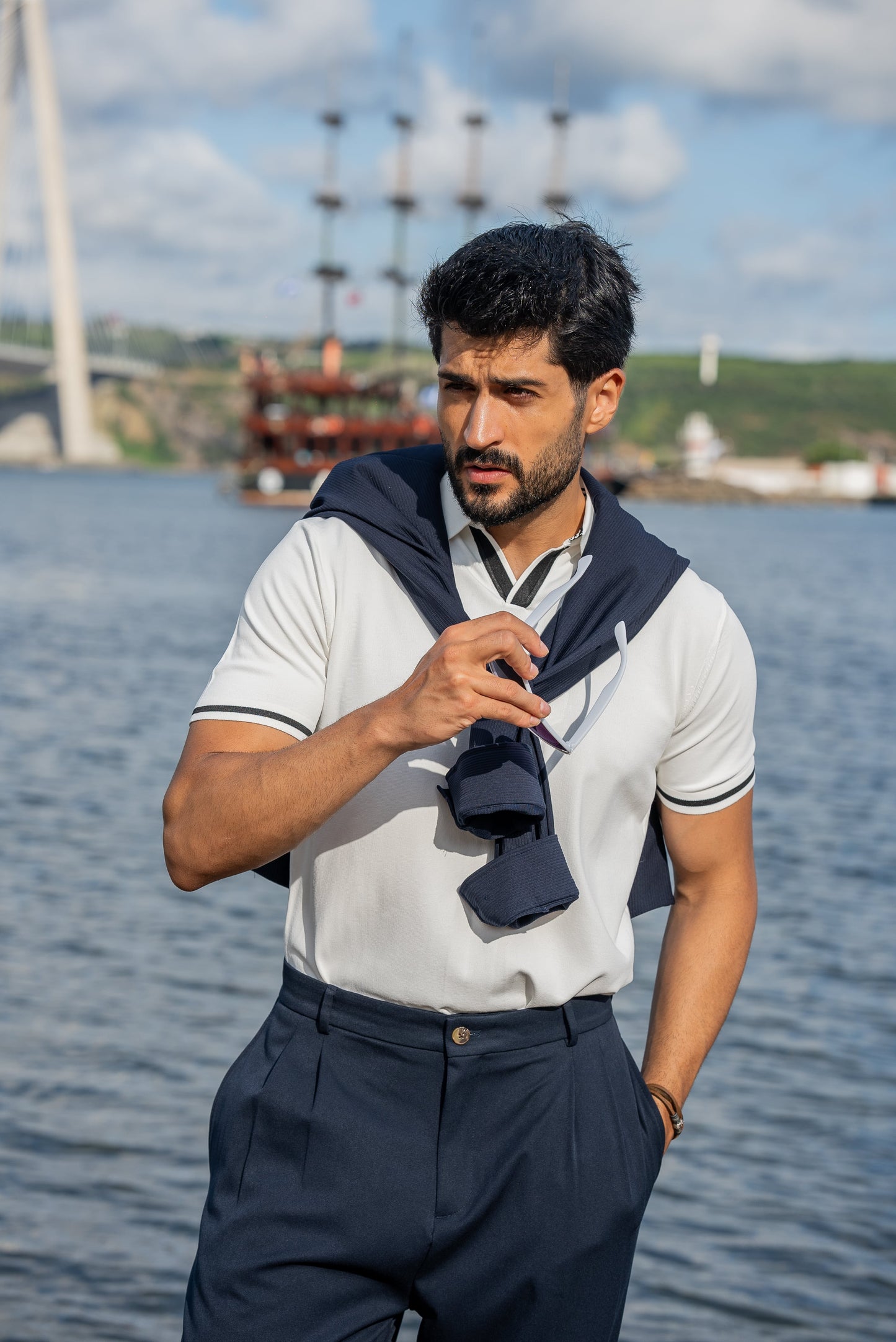 Stylish summer outfit featuring a white polo t-shirt, navy wide-leg trousers, and white sneakers, perfect for a breezy coastal stroll by the water.