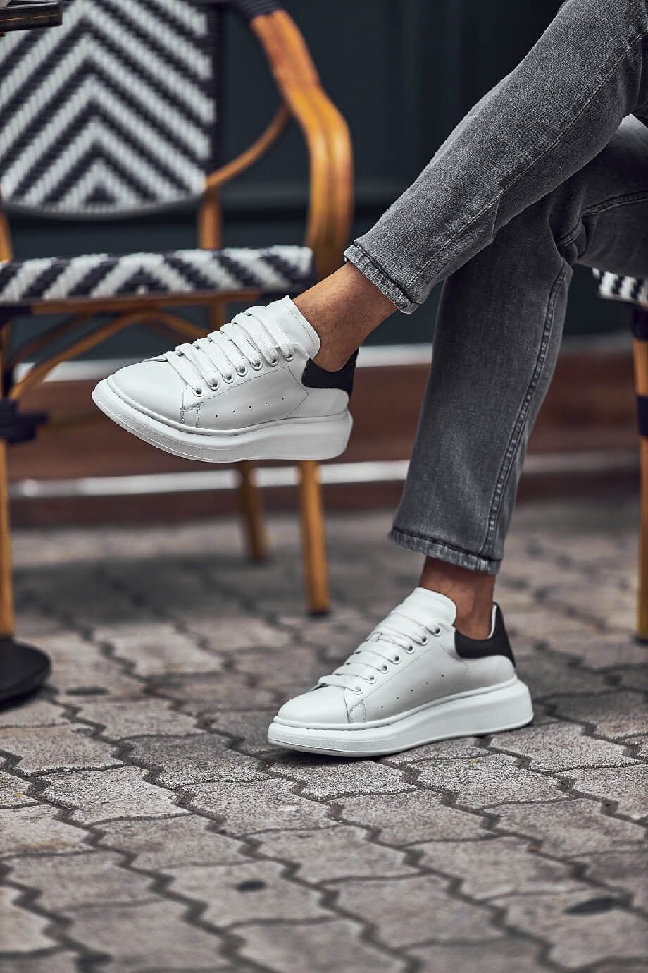White leather sneakers with black heel detail worn with grey jeans