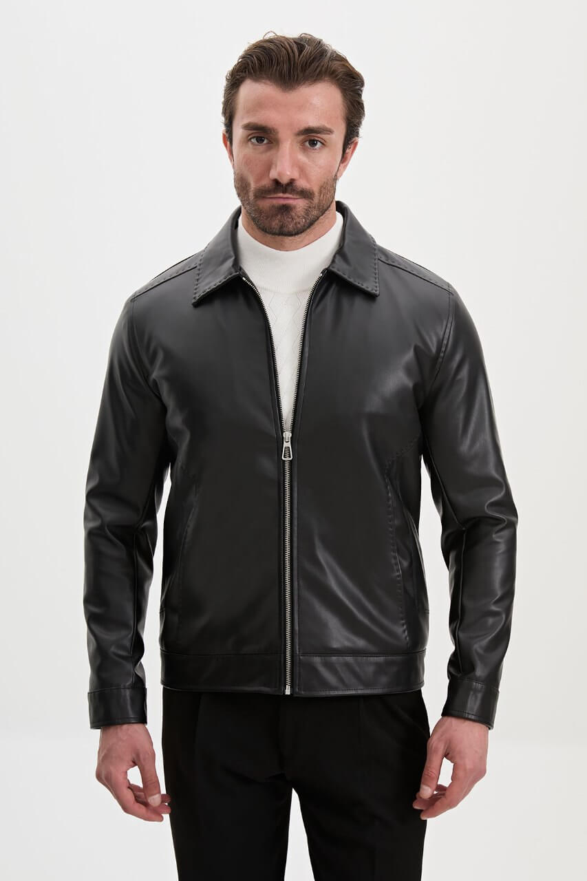 Men's black leather-look jacket styled with a cream knit sweater and black trousers.