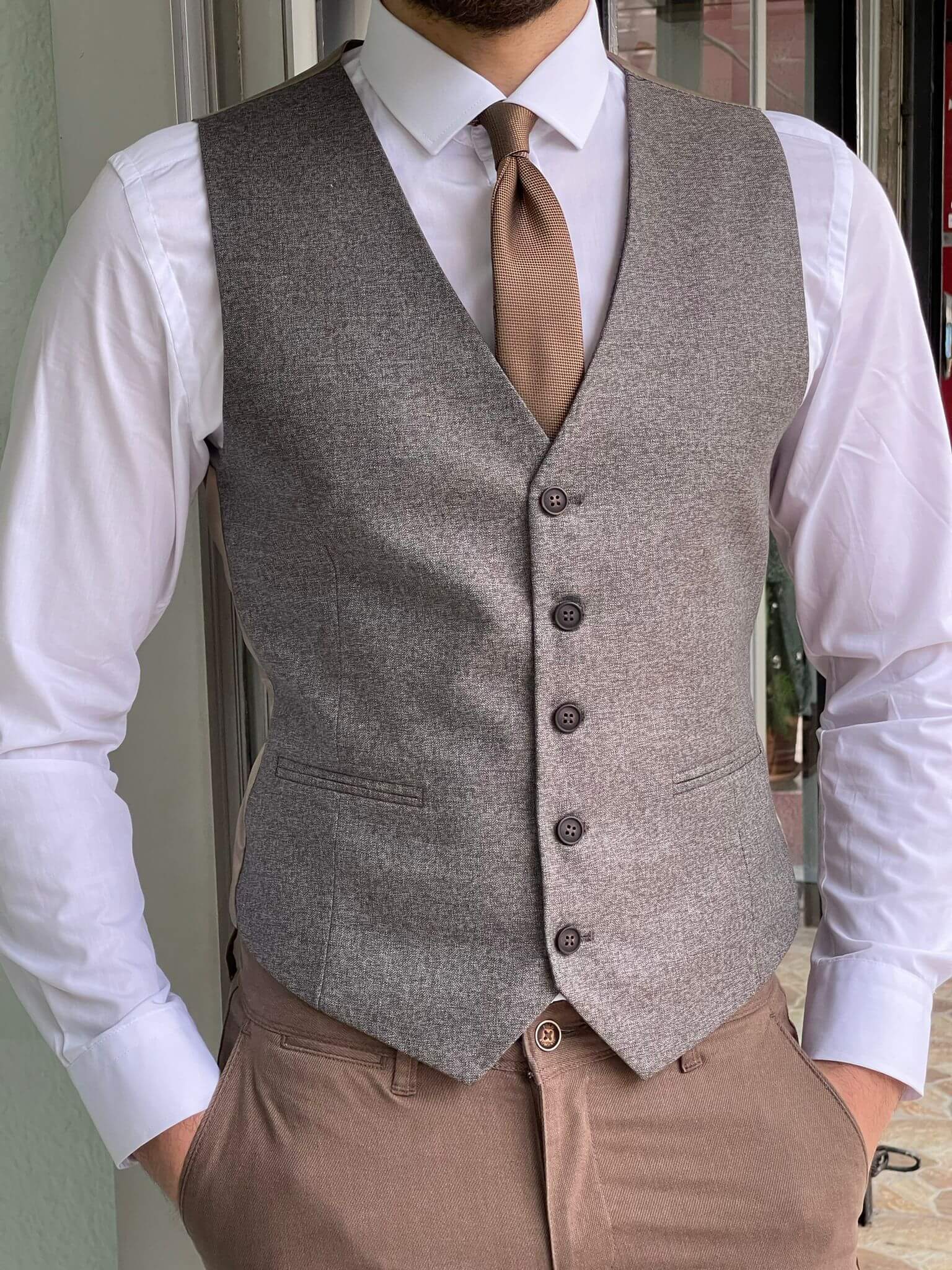 A close-up of a beige waistcoat with buttons and a V-neckline