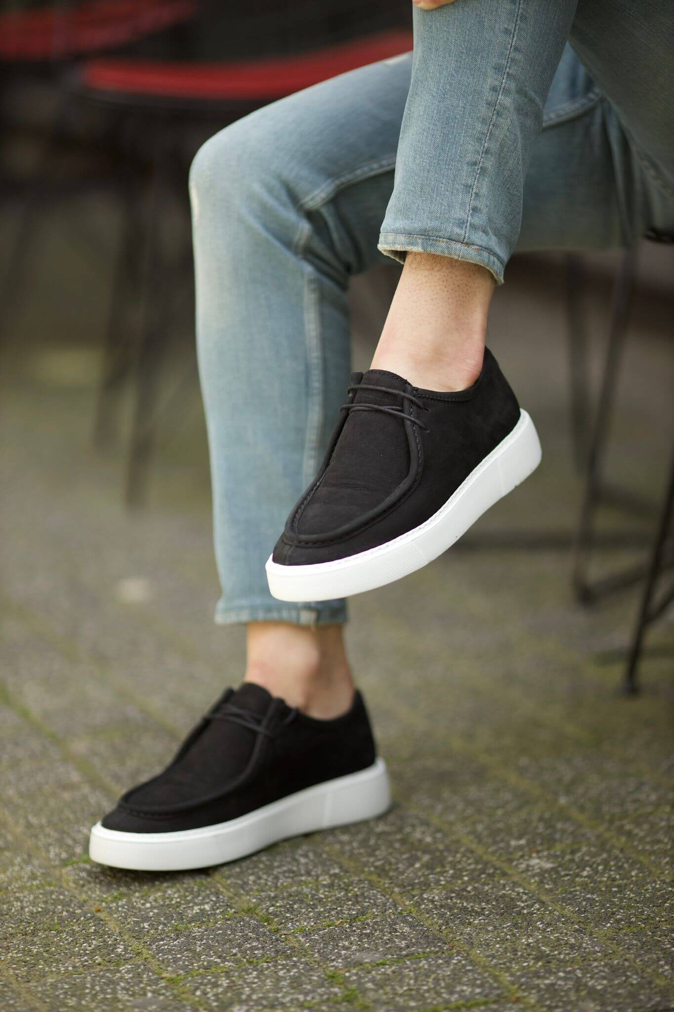 A seated man wears the Cairo Black Suede Derby with ankle-length jeans, showing off the contrast white sole.
