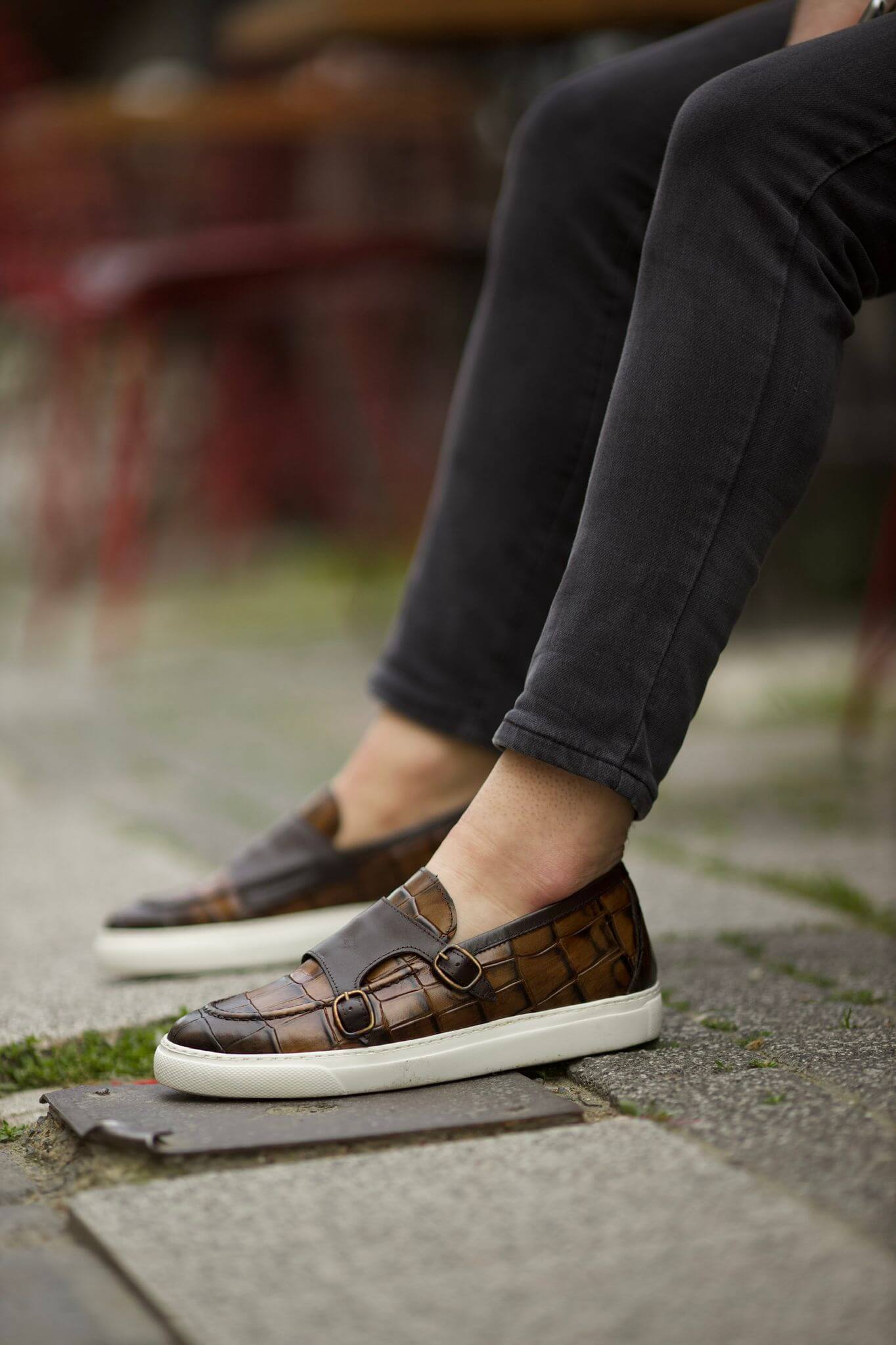 brown leather monk sneakers with embossed texture and dual buckles.