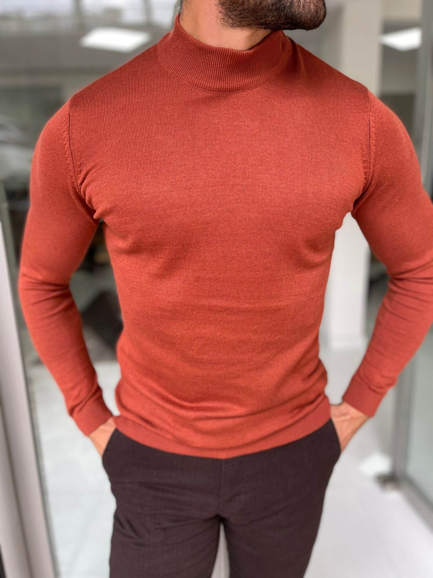 A Hollo Tile Turtlrneck sweater has a high neckline and is made from a soft, textured fabric, providing both warmth and a fashionable look."
