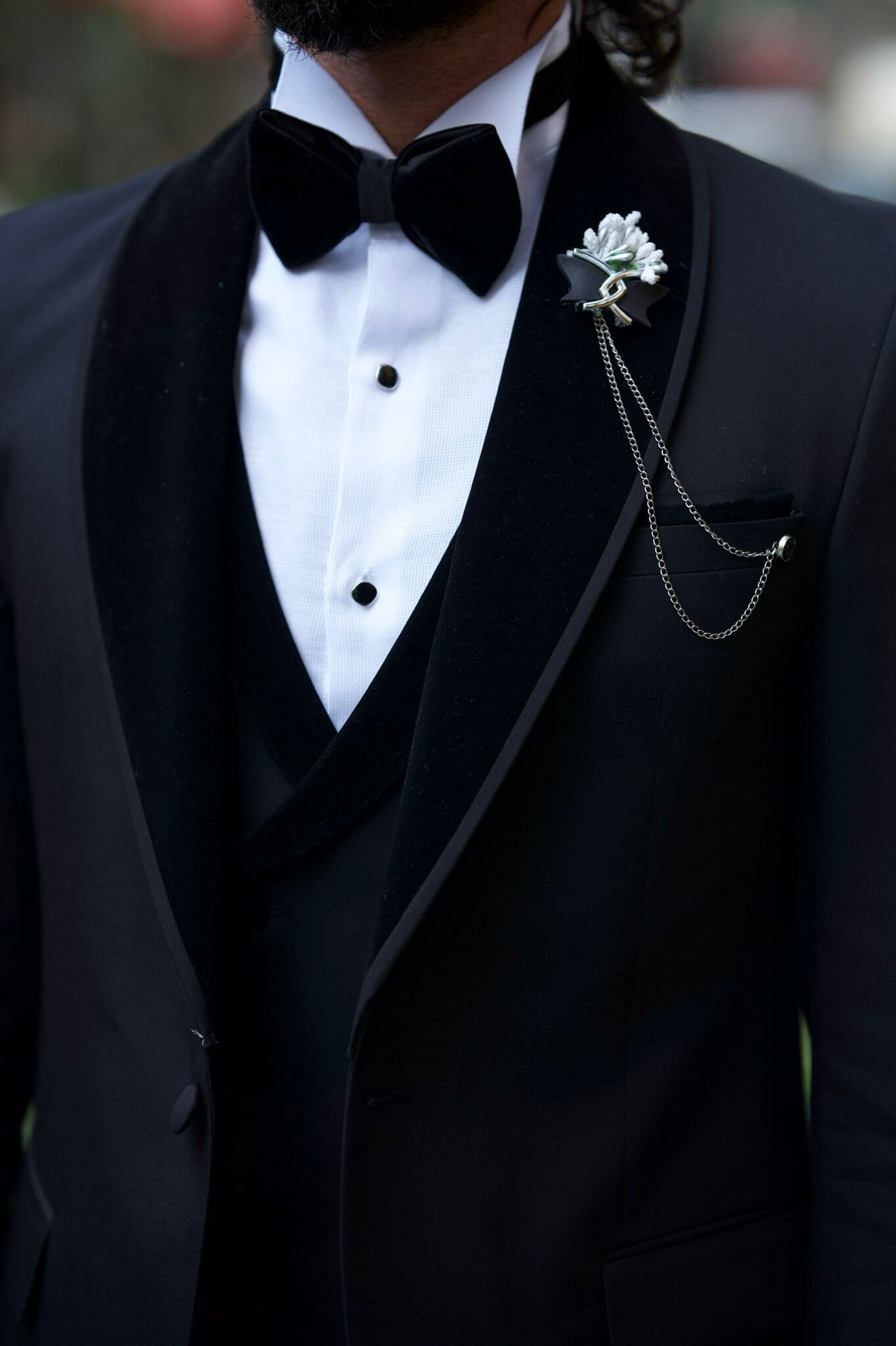 Slim Fit Black Tuxedo from HolloMen’s Spring Summer Collection featuring a shawl collar, double slits, single button, and full formal package with vest, pants, shirt, bowtie, chain, and flower pin – perfect for weddings and black-tie events.