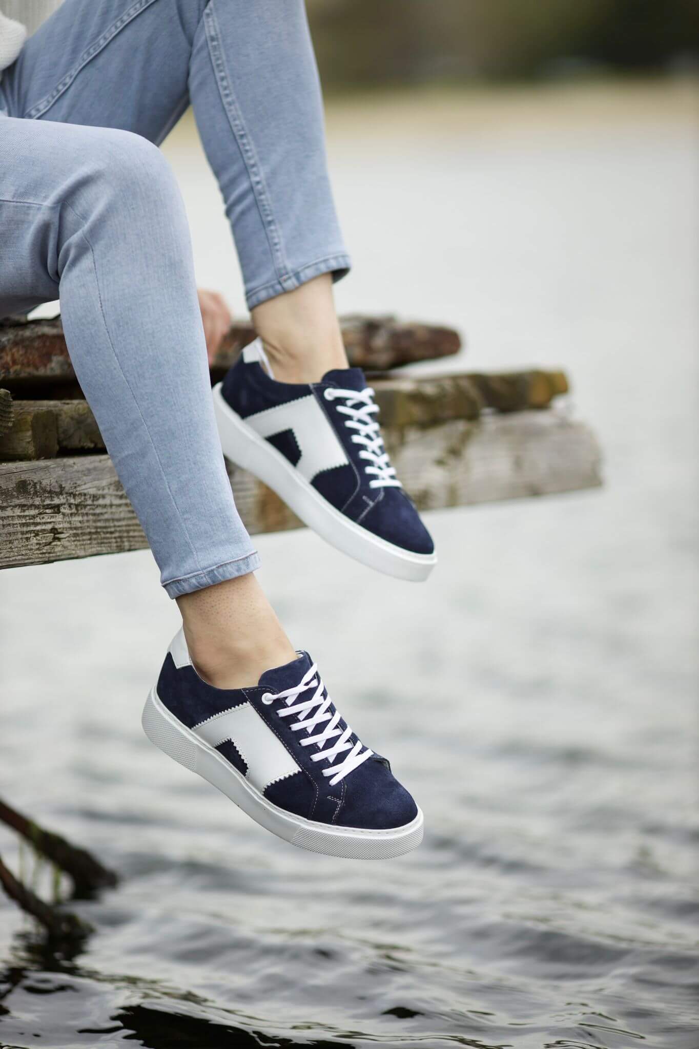 Navy and white leather sneakers on feet, styled by the waterfront