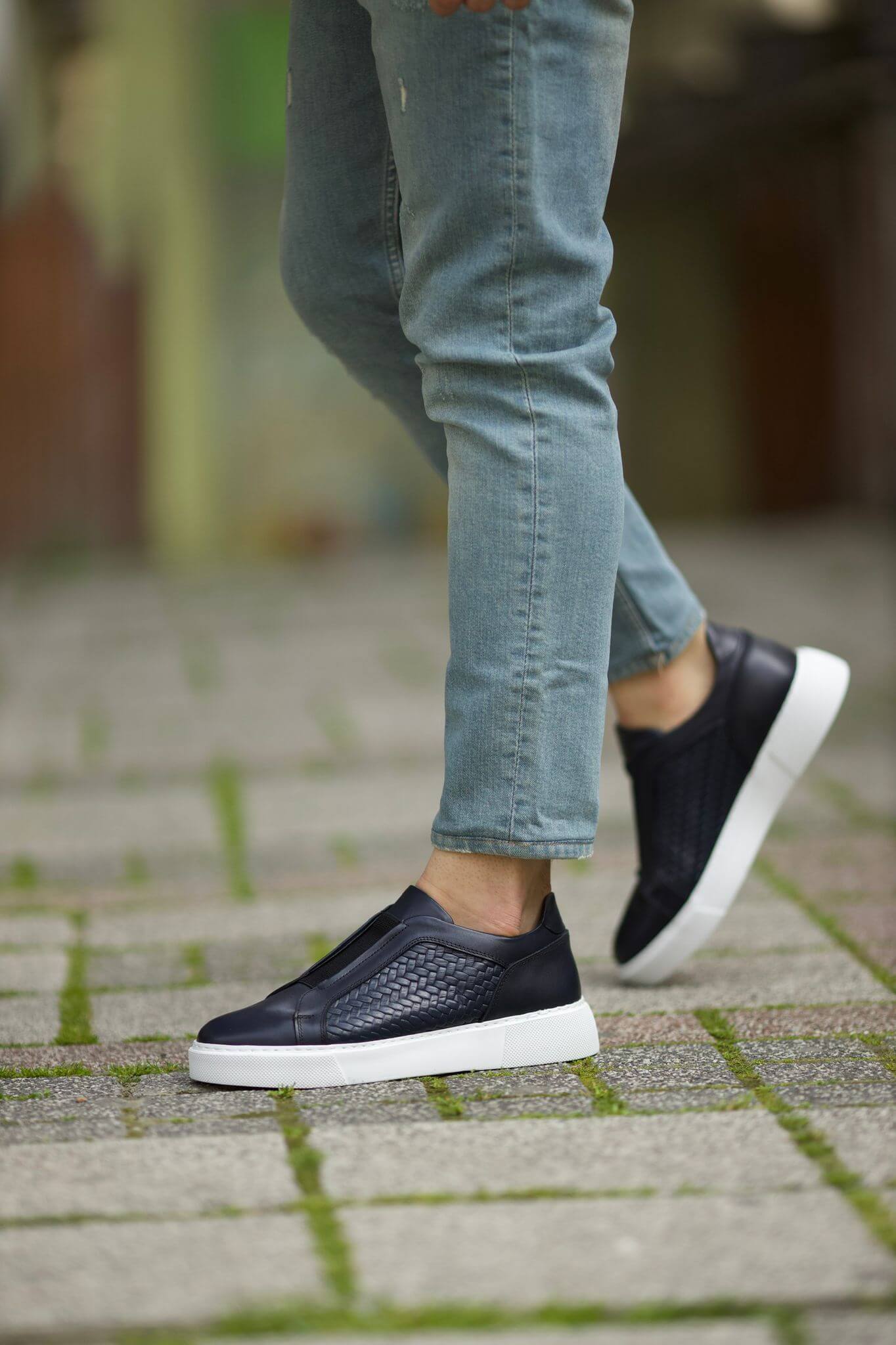 Navy Blue leather slip-on sneakers with basket-weave detailing, worn casually outdoors.