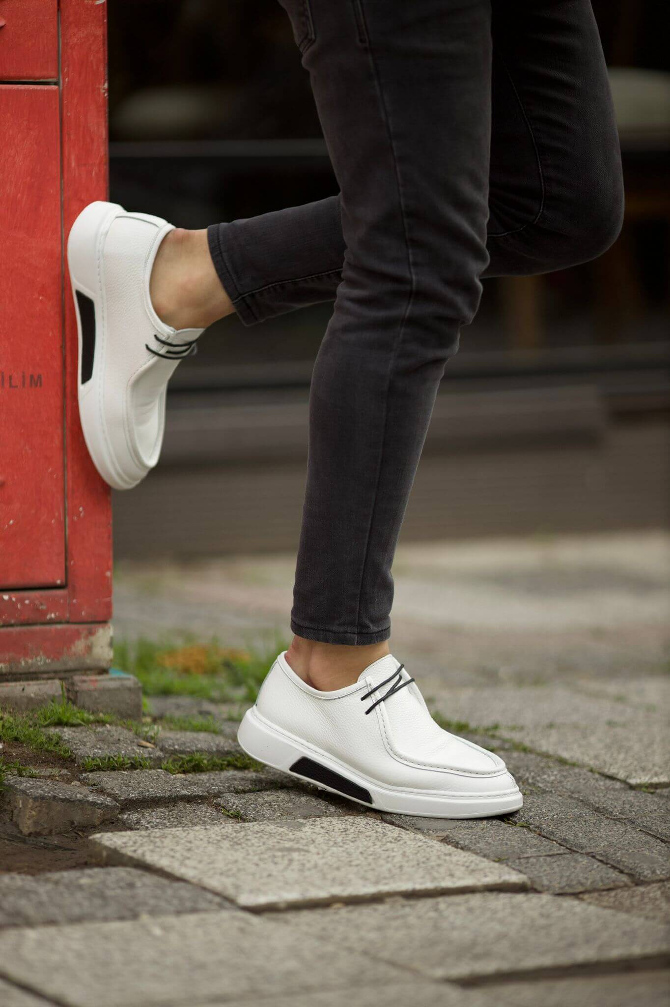 White leather derby shoes with black laces and EVA sole, styled with charcoal pants.